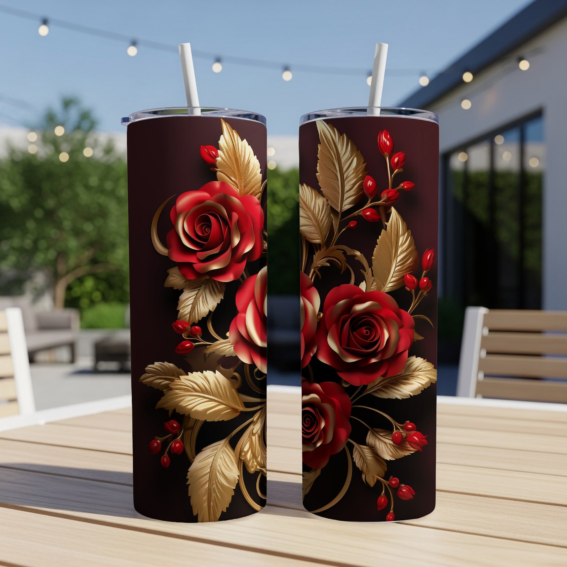 Two dark red tumblers with gold rose and berry designs on a table.