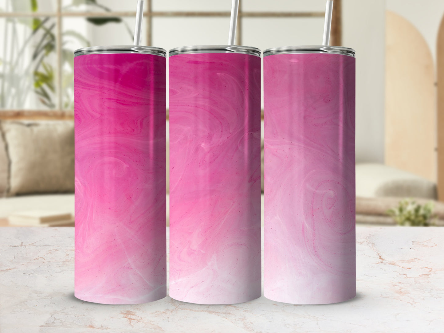Three pink marbled tumblers with straws in a studio setting.