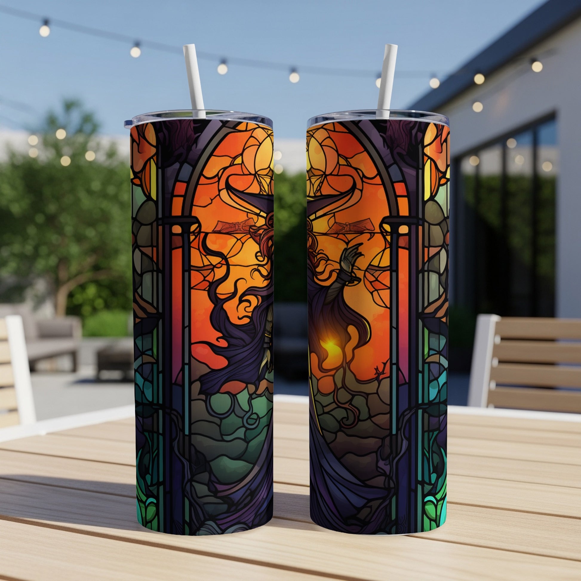 Two stained glass tumblers with gothic witch design on outdoor table.