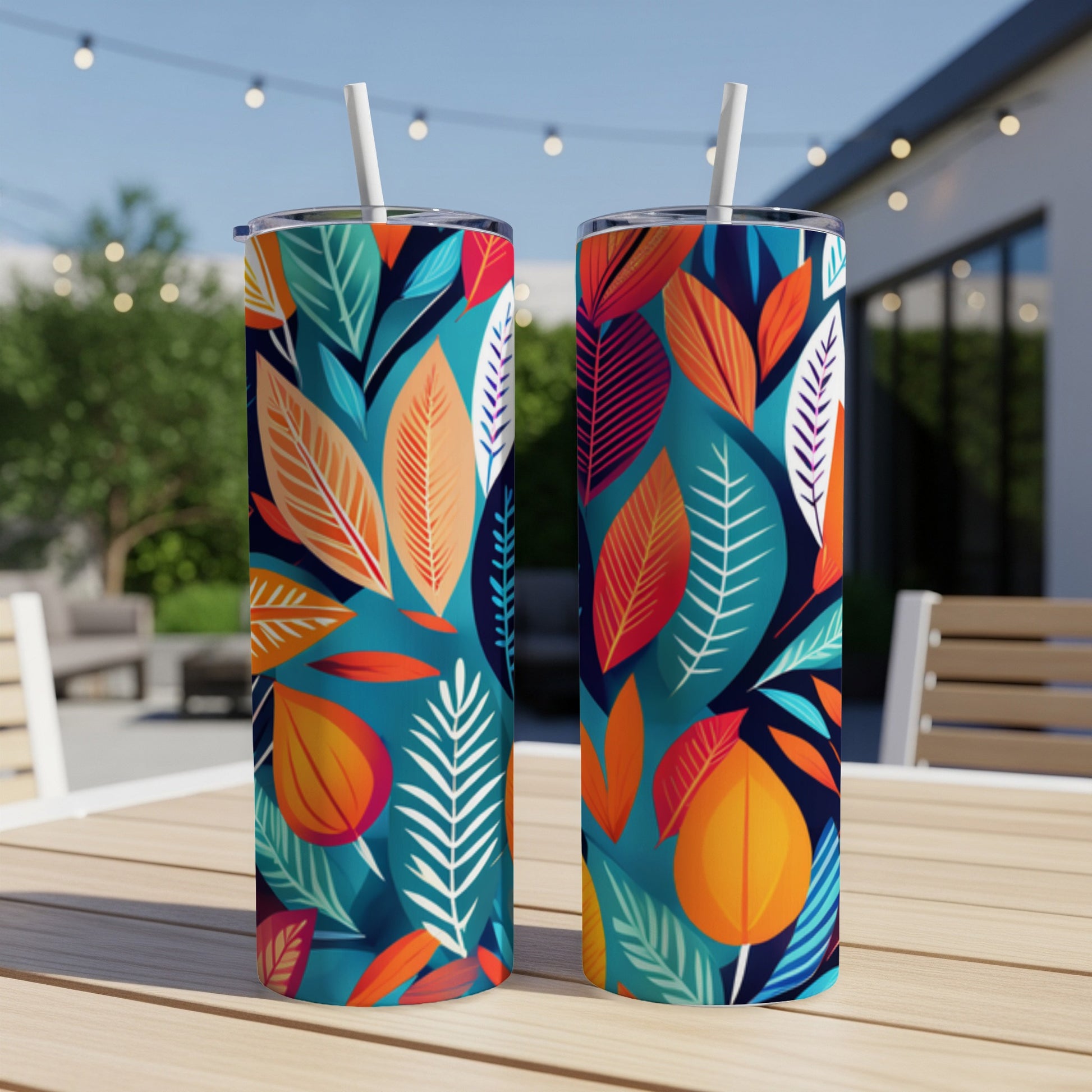 Two tall tumblers with a vibrant tropical leaf pattern, resting on a wooden table outdoors.