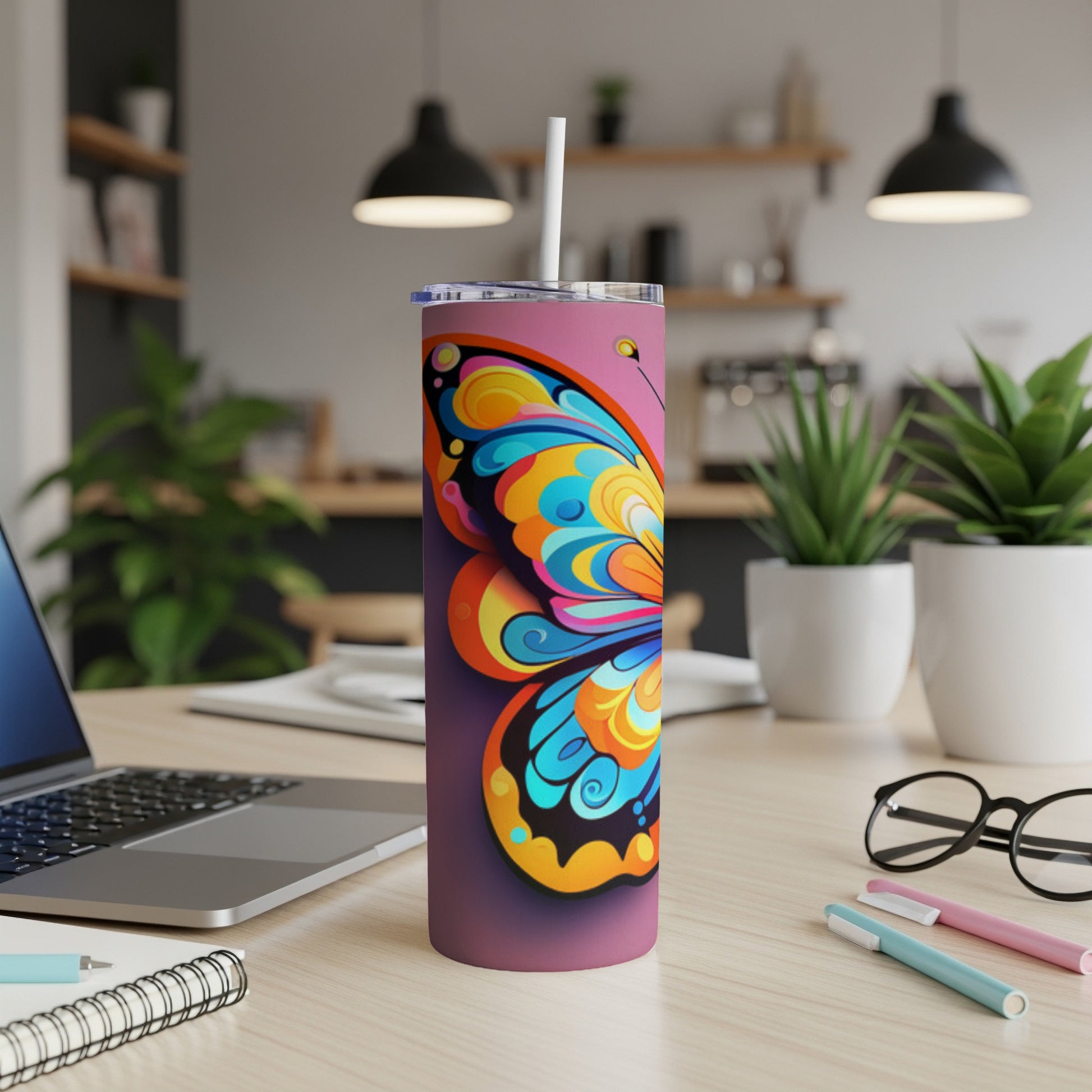 Purple tumbler with vibrant, colorful butterfly design, straw, on a desk.