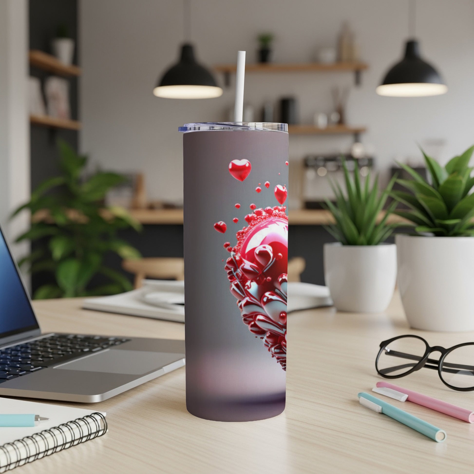 Tumbler with red metallic hearts and a white straw on a desk.