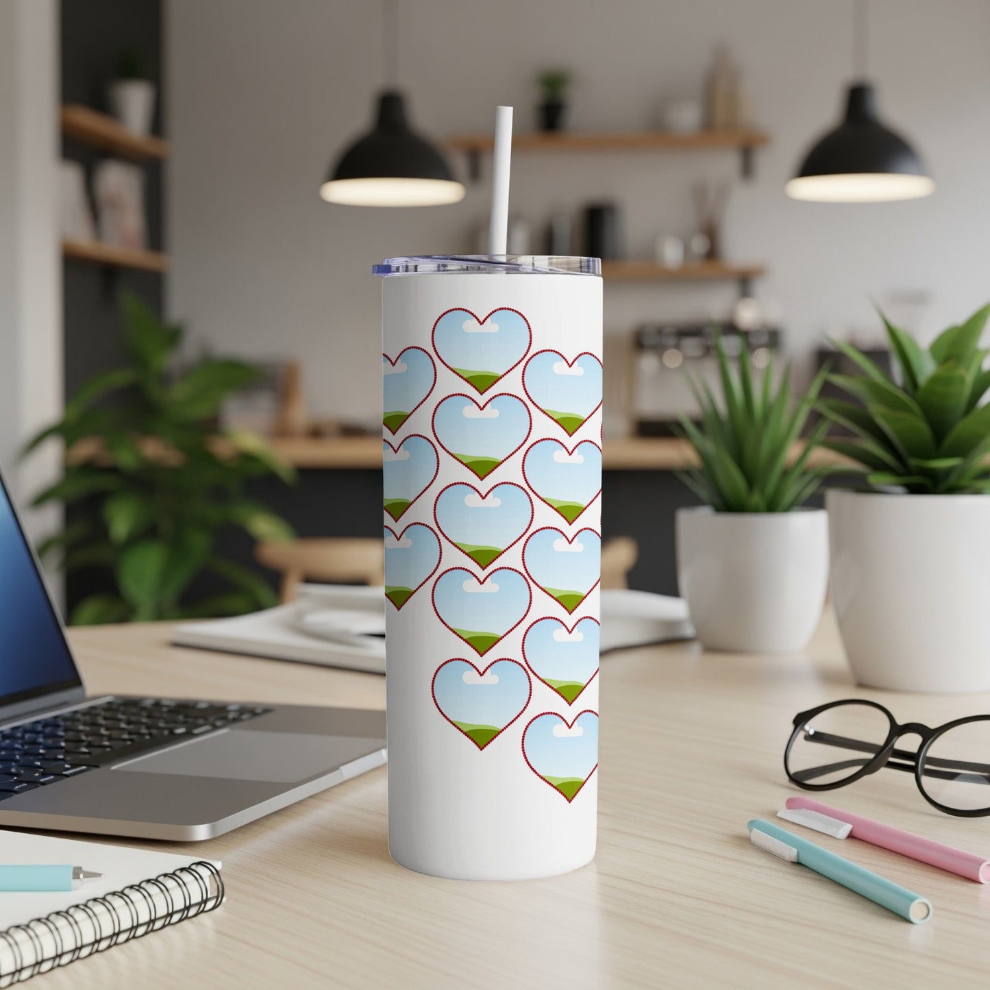 White tumbler with a repeating pattern of hearts filled with sky and grassy hills.