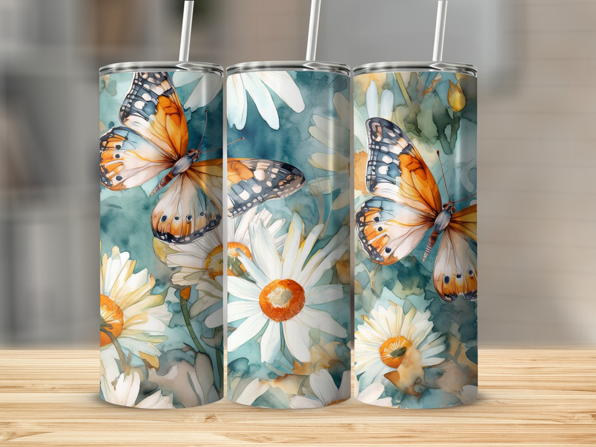 Three tumblers featuring watercolor butterflies and daisies on a blue-green background.