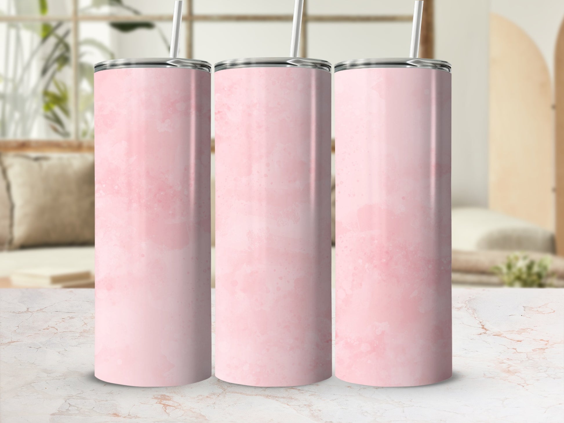 Three pink watercolor tumblers with straws on a marble surface.