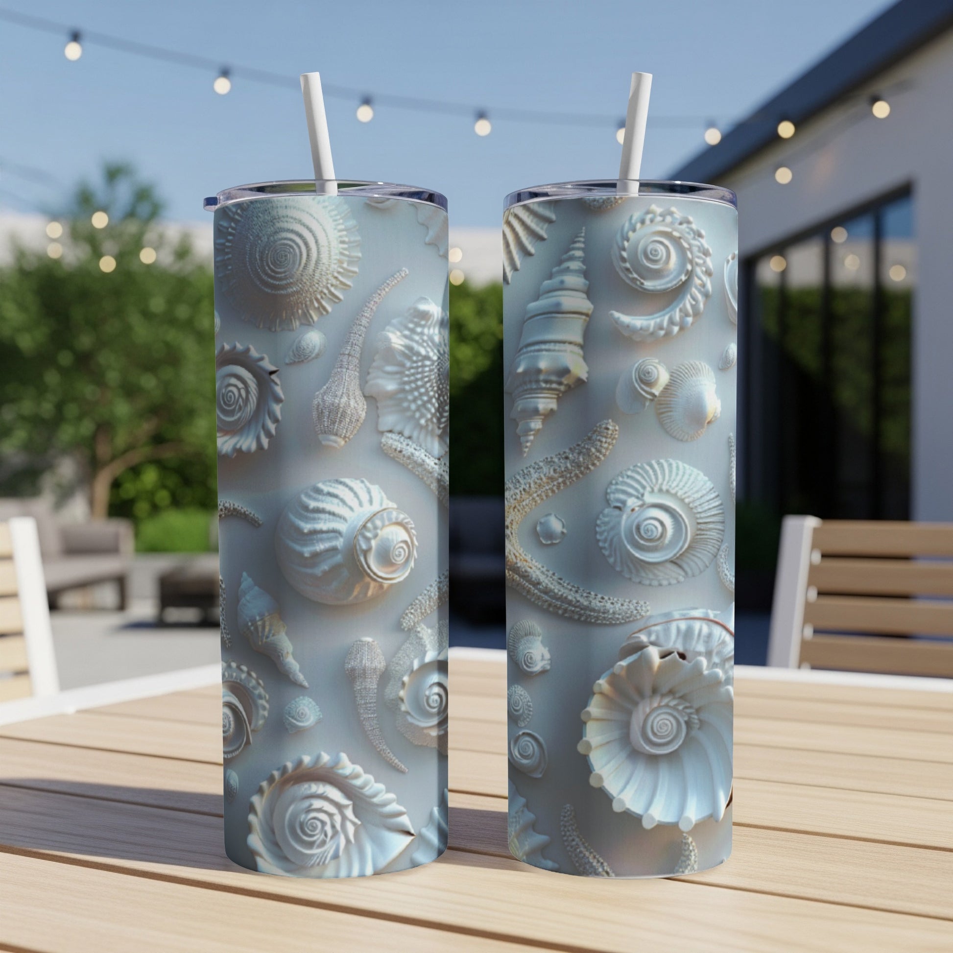Two tall tumblers with intricate seashell patterns on a wooden table.