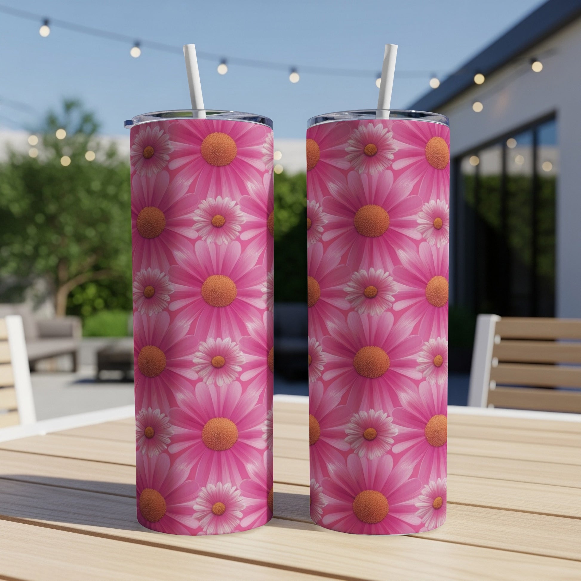 Two pink floral tumblers with straws sit on a wooden table.