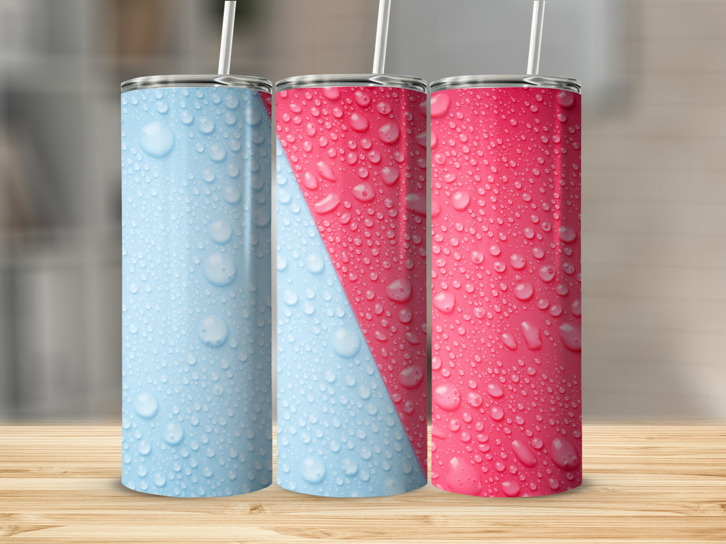 Three tumblers with water droplet patterns in blue and pink on a wooden surface.