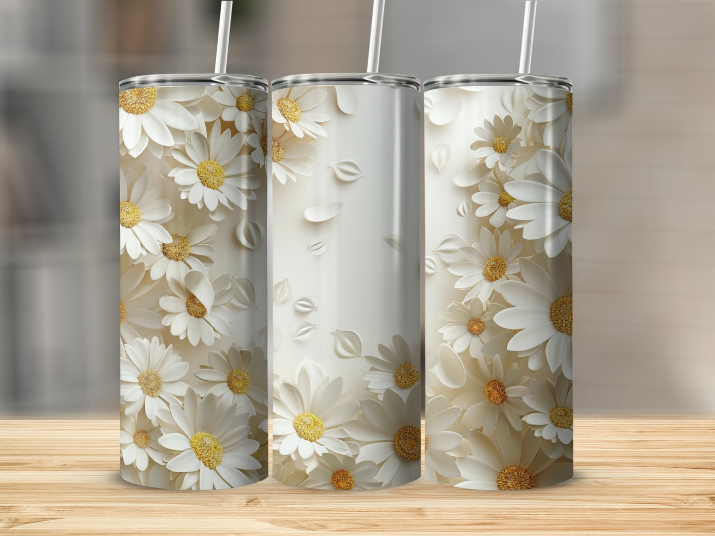 Three white daisy patterned tumblers with straws on a wooden surface.