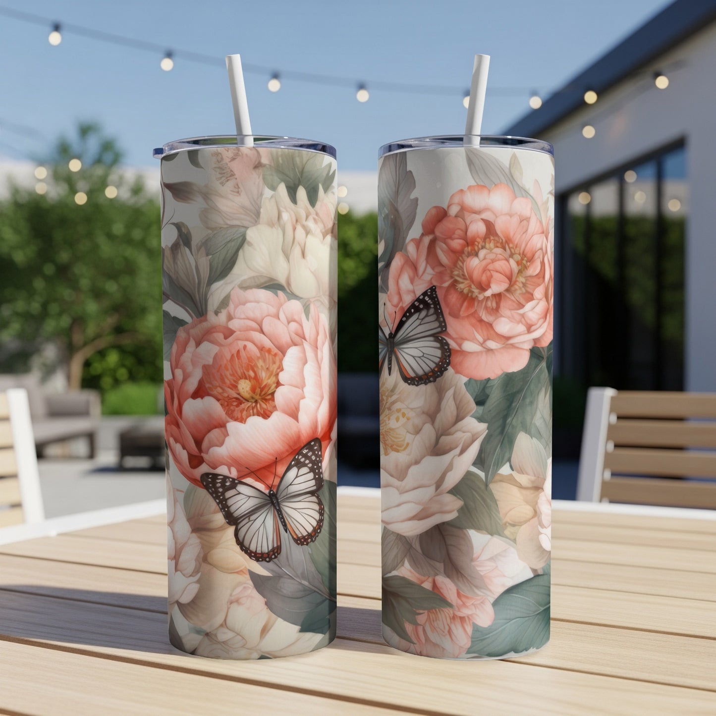 Two tumblers with floral and butterfly designs on a wooden table.