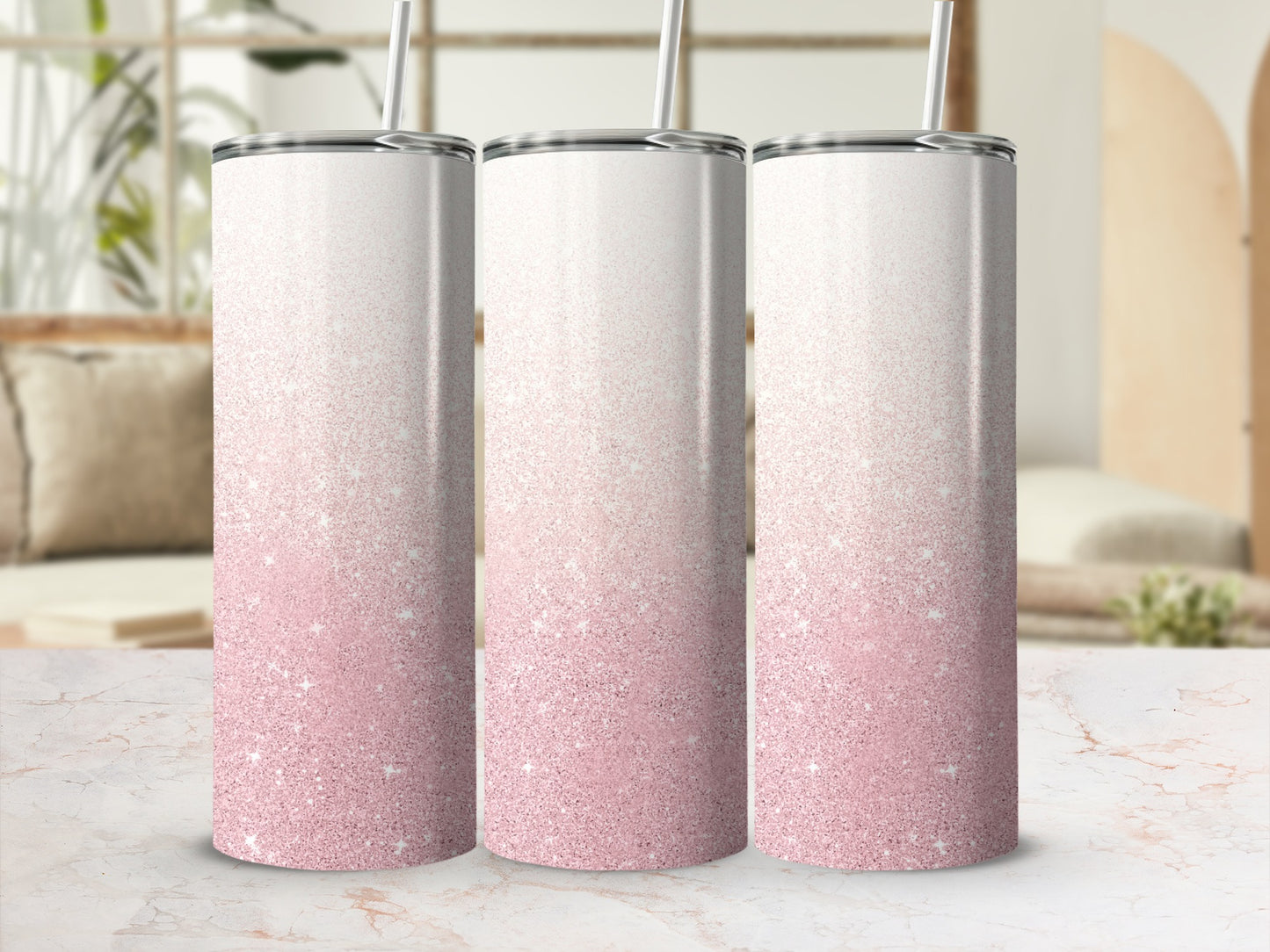 Three skinny tumblers with pink glitter gradient and straws, on a marble surface.