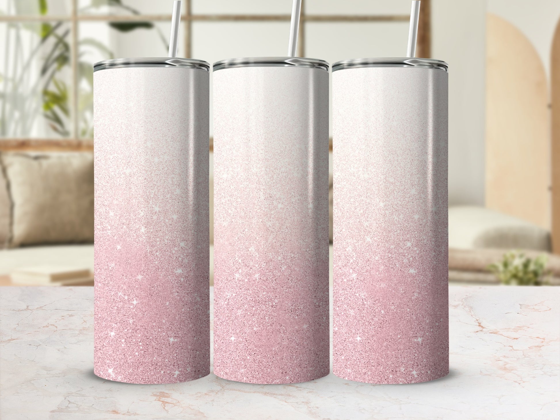 Three skinny tumblers with pink glitter gradient and straws, on a marble surface.