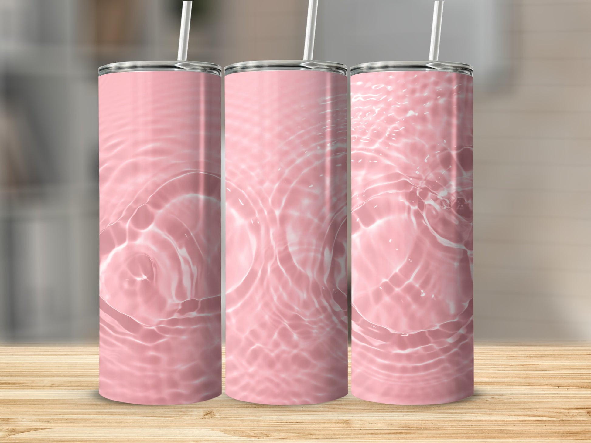 Three pink tumblers with rippling water design on a wooden surface.