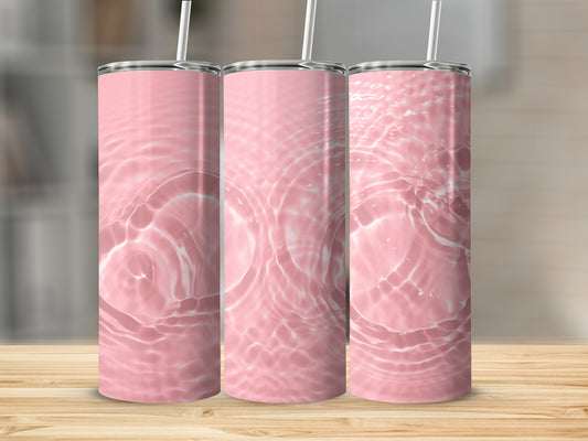 Three pink tumblers with rippling water design on a wooden surface.