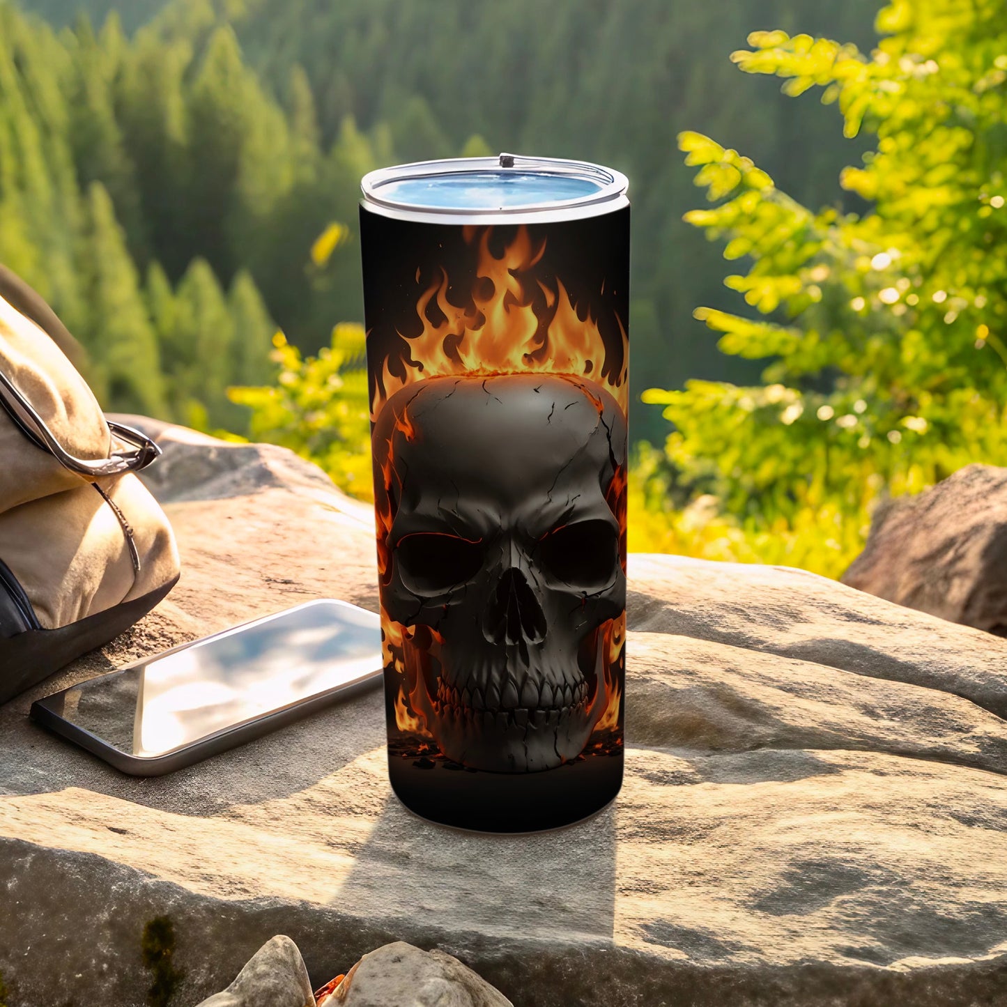 Black skull with fiery accents on a black tumbler, set outdoors.
