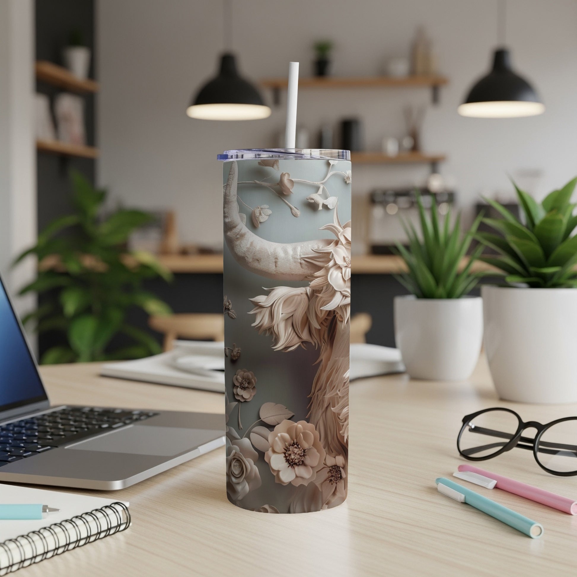 Tumbler with floral and mythological creature design on desk.