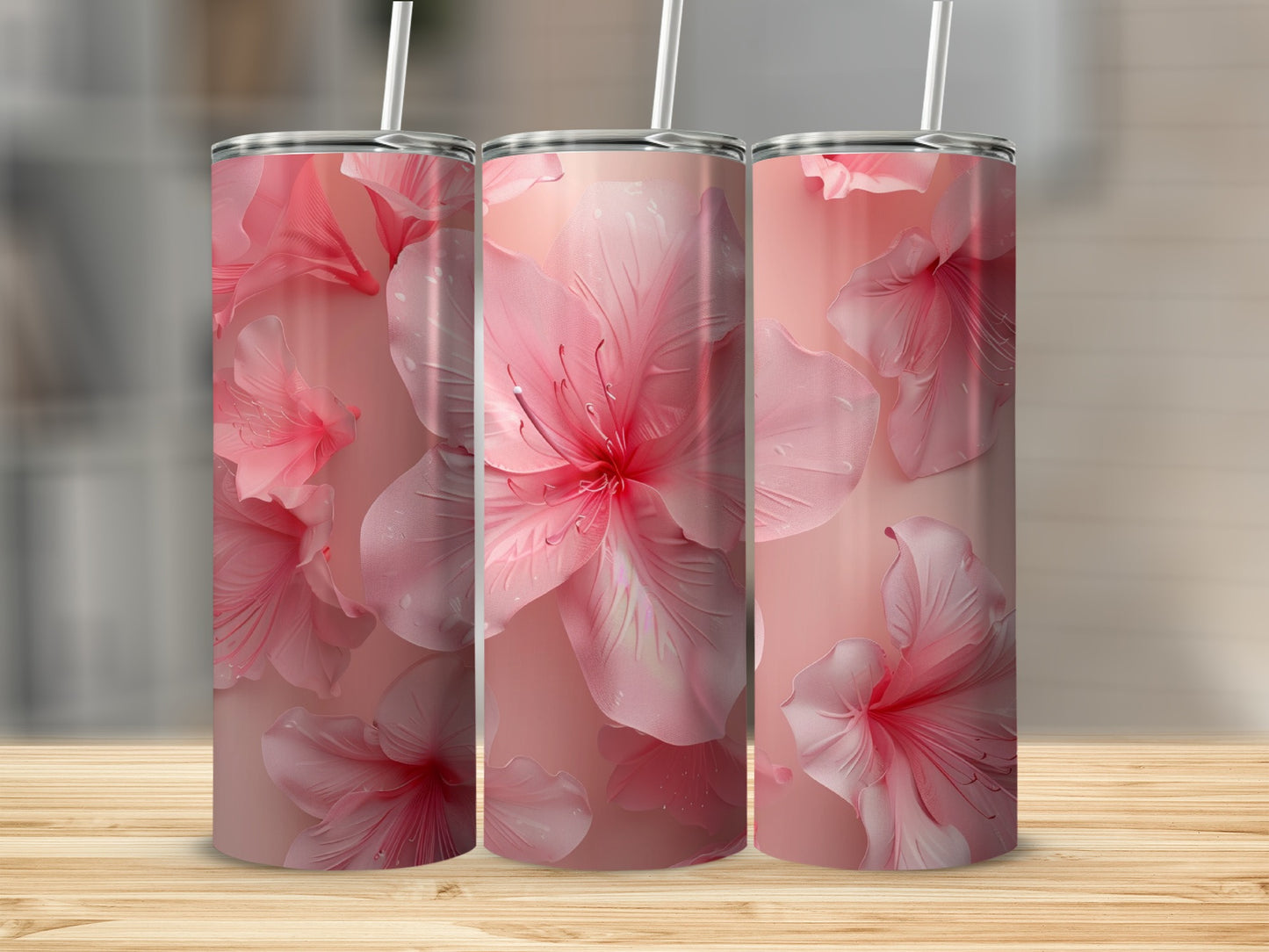 Three pink floral tumblers with straws on a wooden surface.