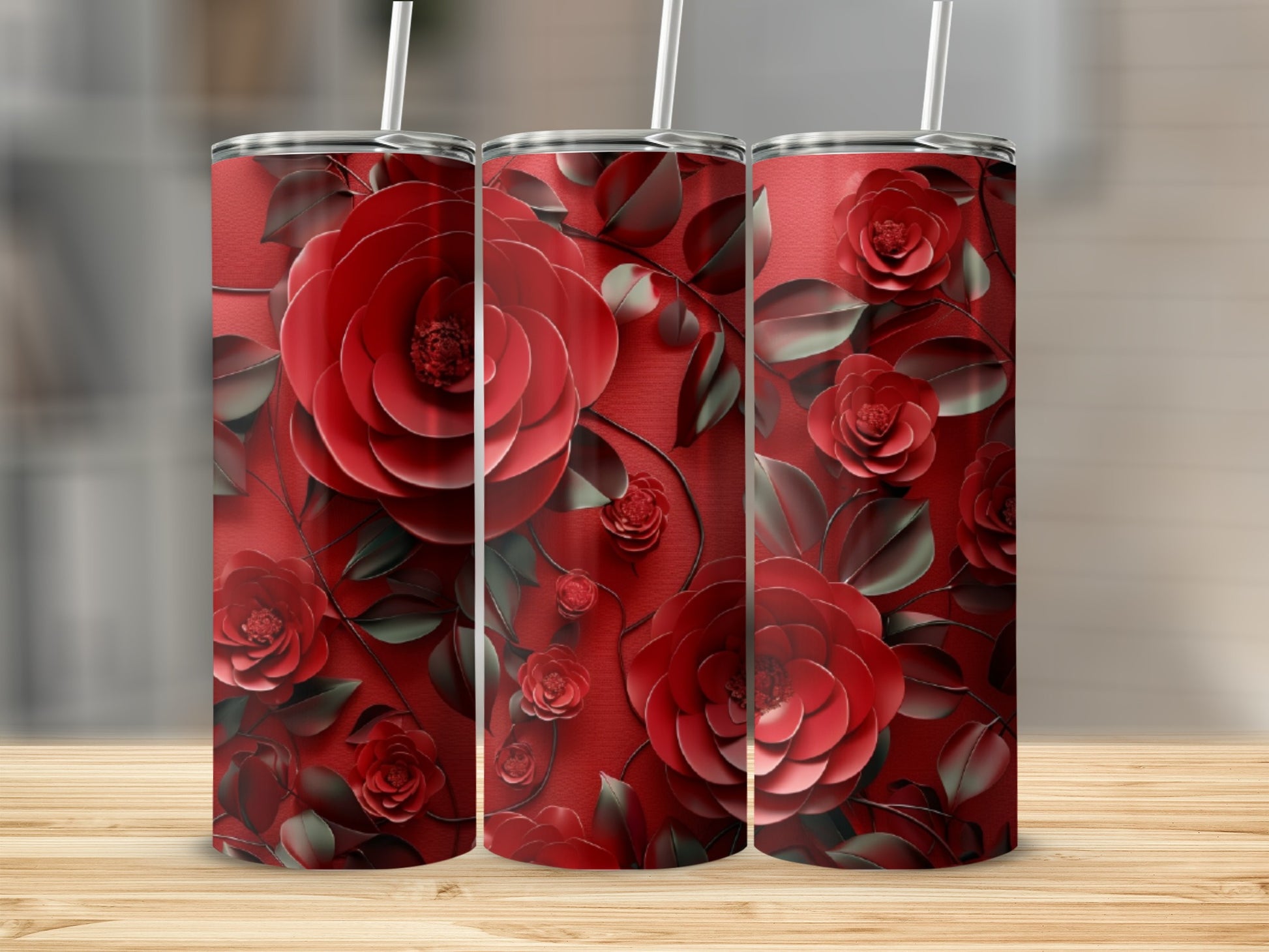 Three tumblers with a dark red rose floral design on a wooden surface.