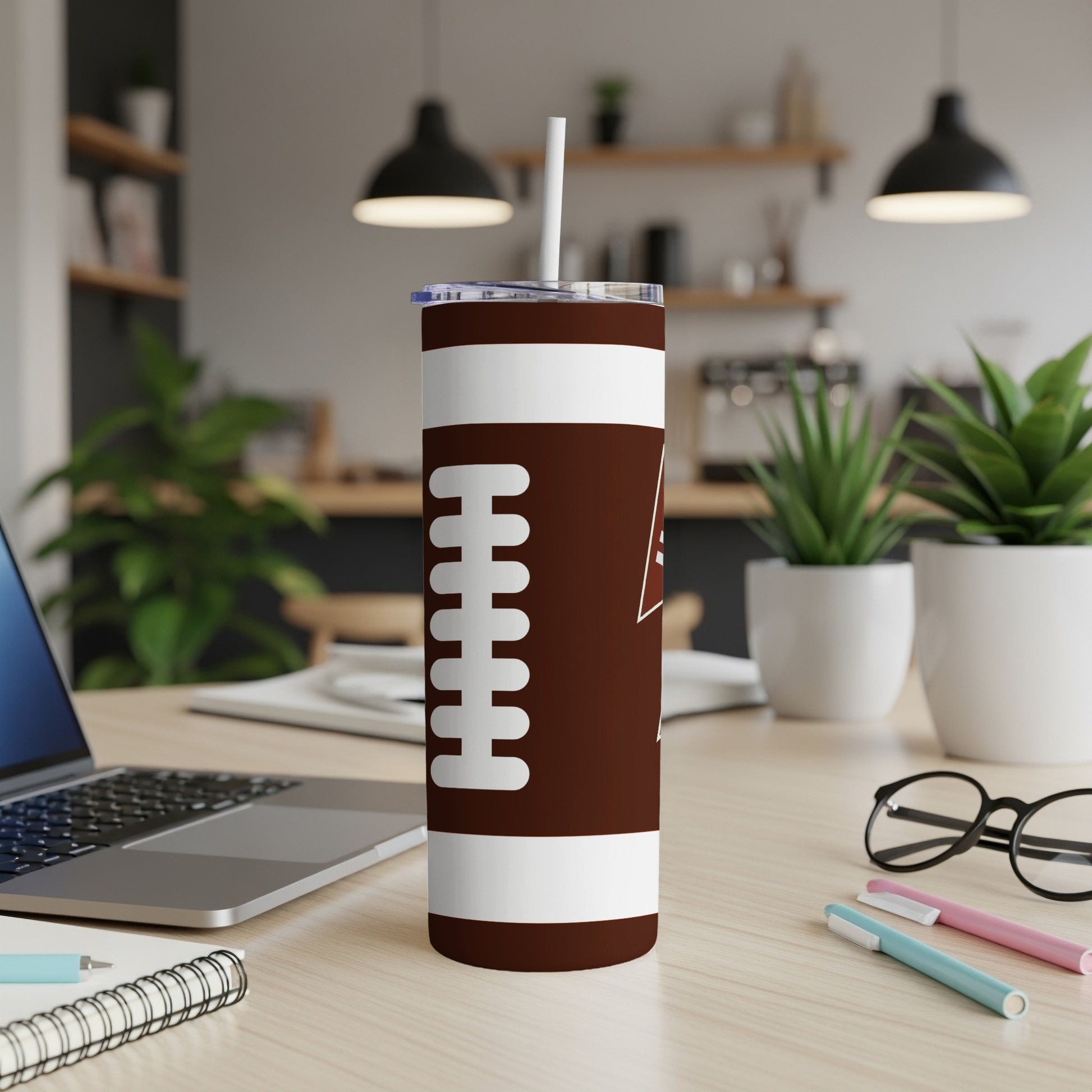 Brown tumbler with white football laces design on a desk.