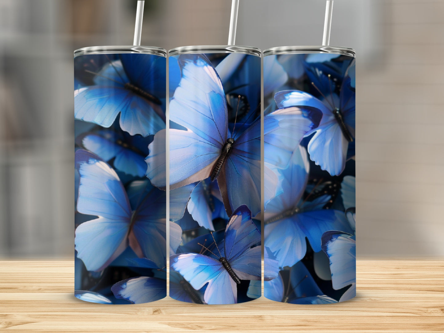 Three tumblers with blue butterfly design on a wooden surface.