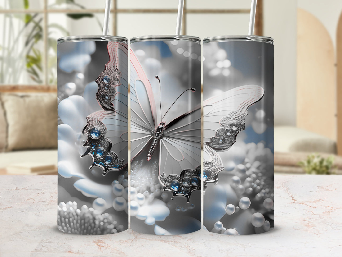 Butterfly and pearl design on a silver tumbler with a blurred background.