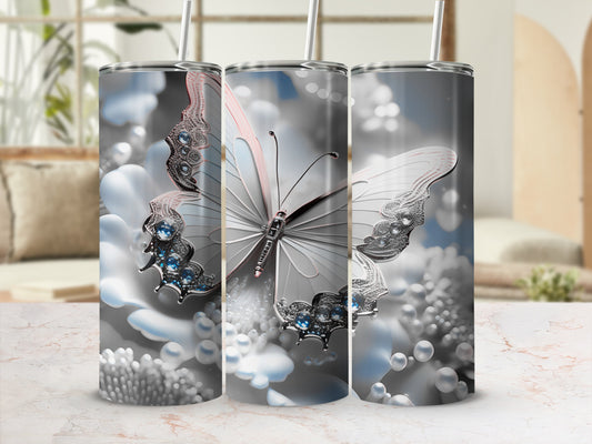 Butterfly and pearl design on a silver tumbler with a blurred background.