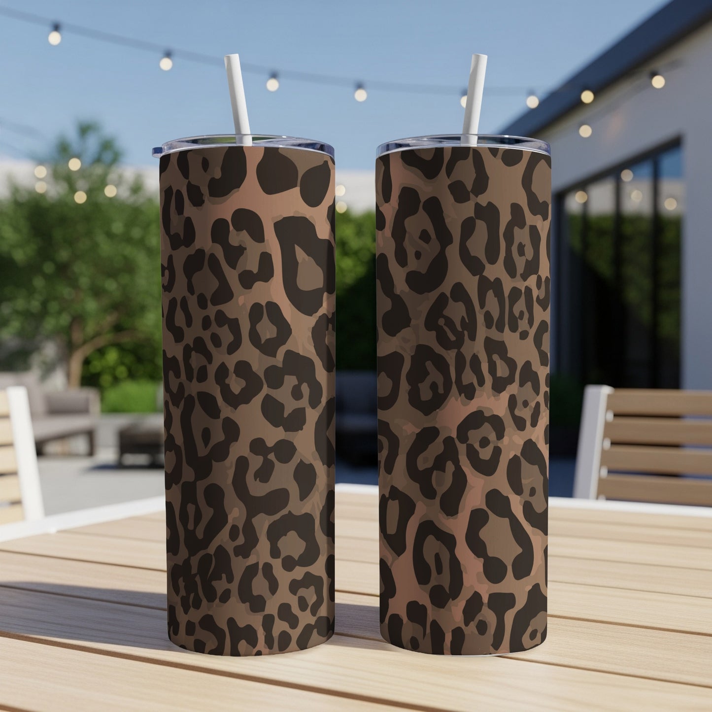 Two leopard print tumblers with white straws on a wooden table.