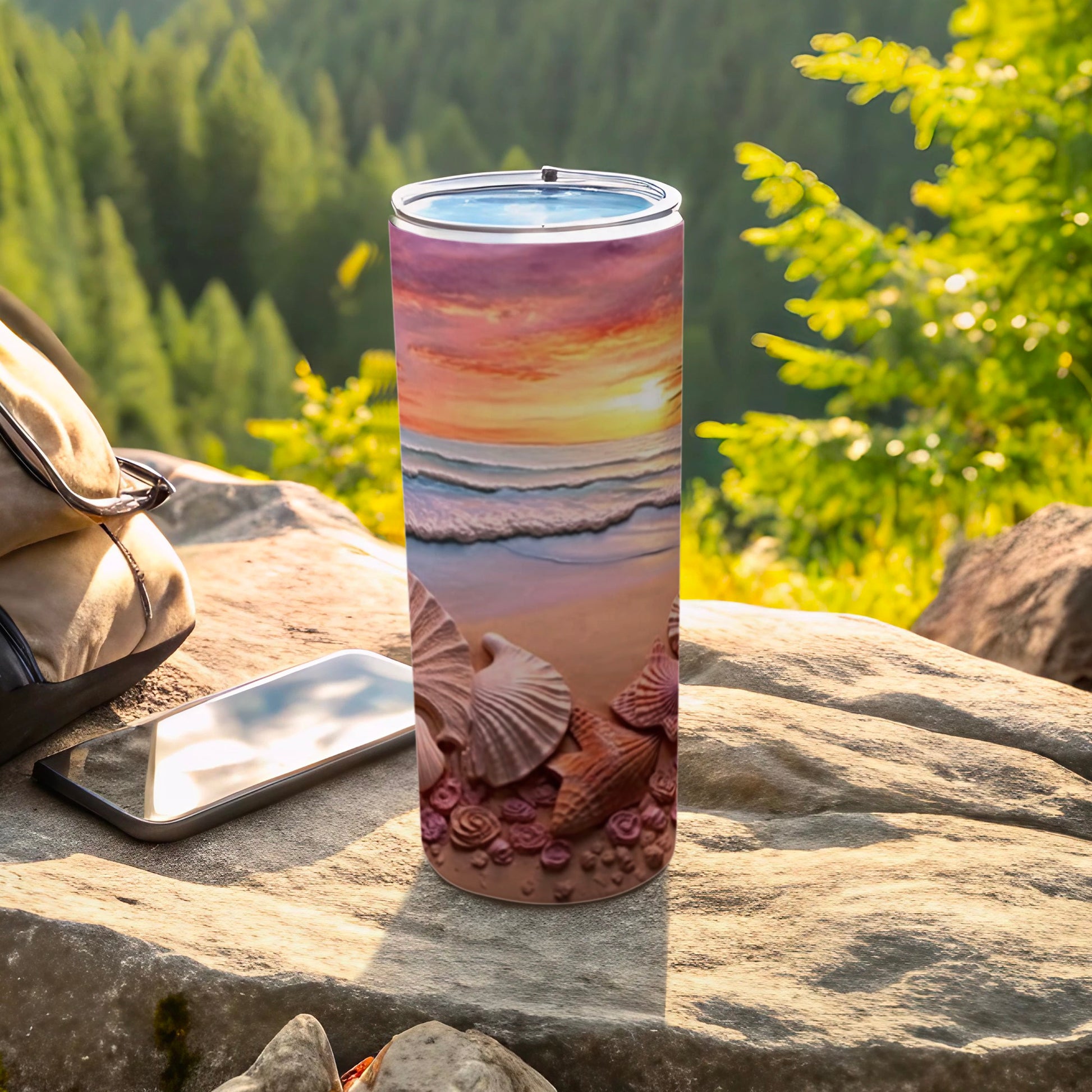Tumbler with a seashell and sunset design on a rocky outdoor surface.
