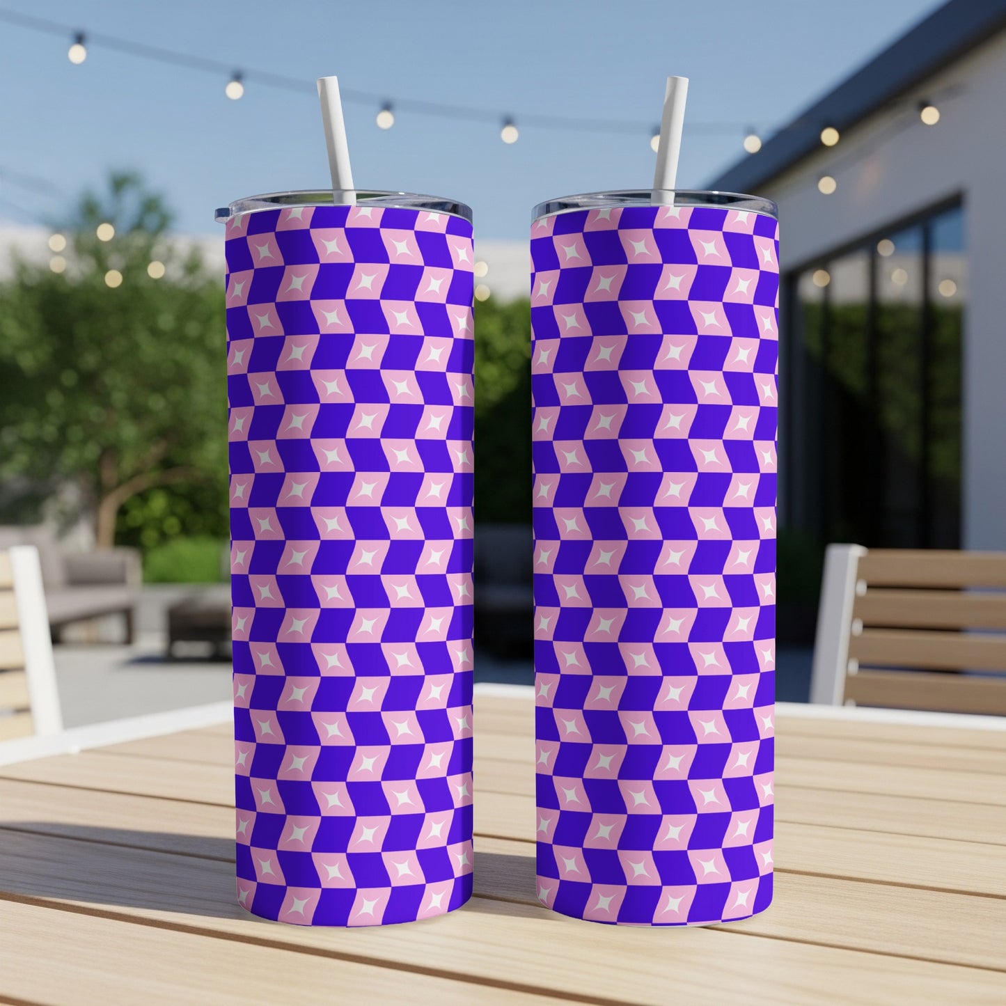 Two tall tumblers with a pink and blue geometric pattern sit on a wooden table.