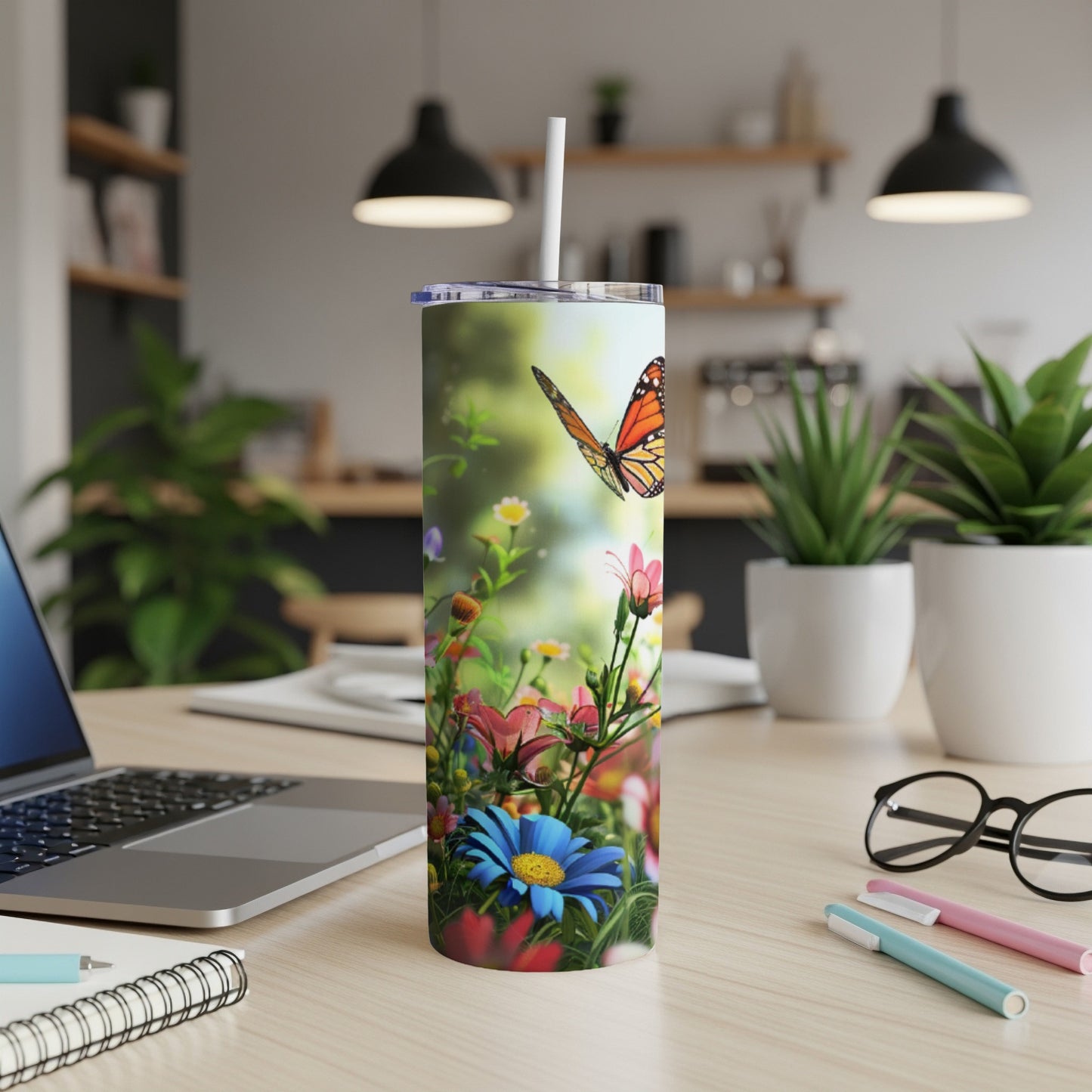 Tall tumbler with butterfly and flowers, resting on a desk.