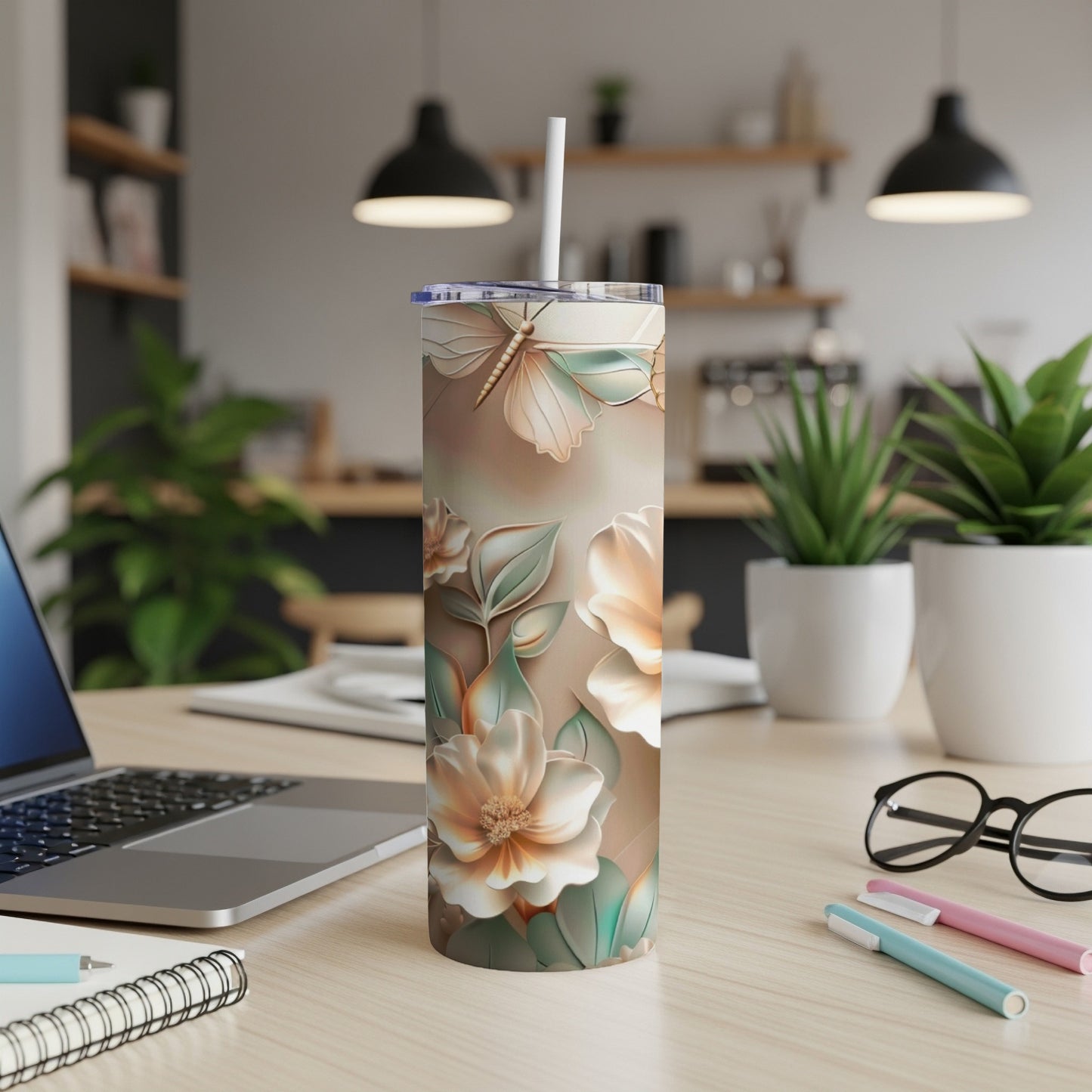 Floral butterfly pattern on a white tumbler with a straw, on a desk.