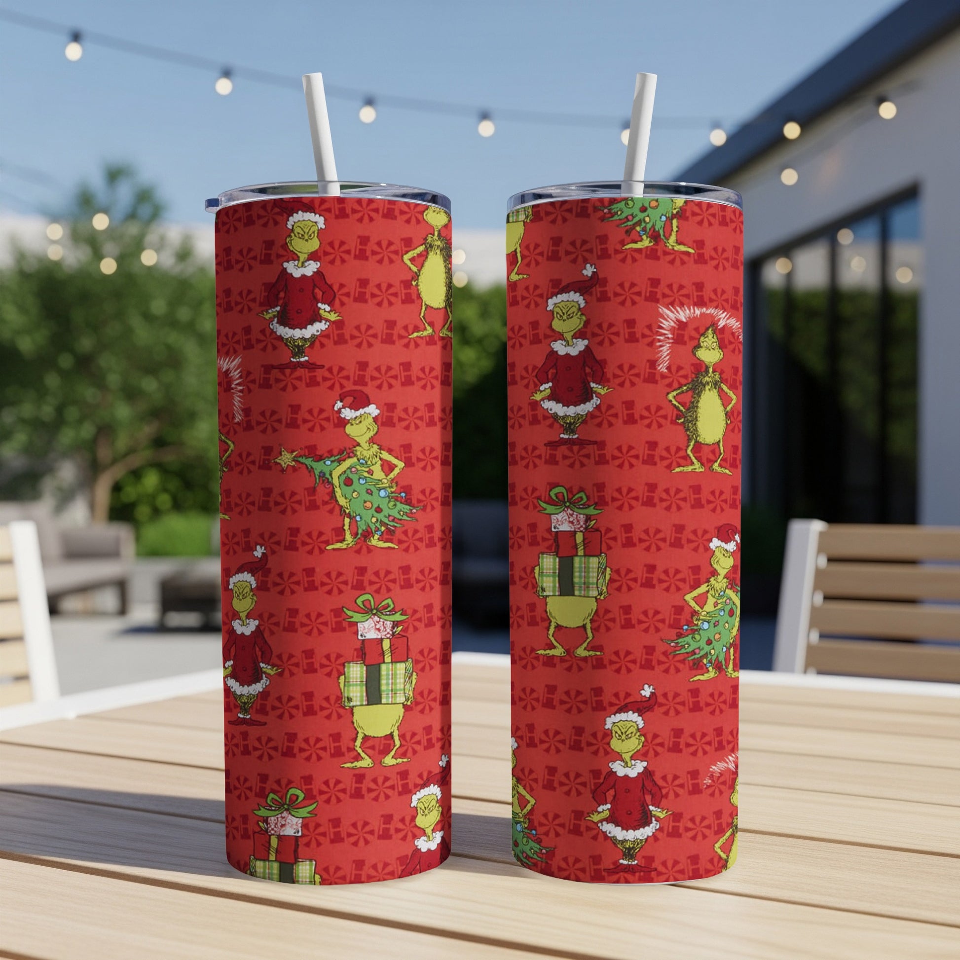 Two Grinch-themed tumblers with straws on a table, holiday pattern.