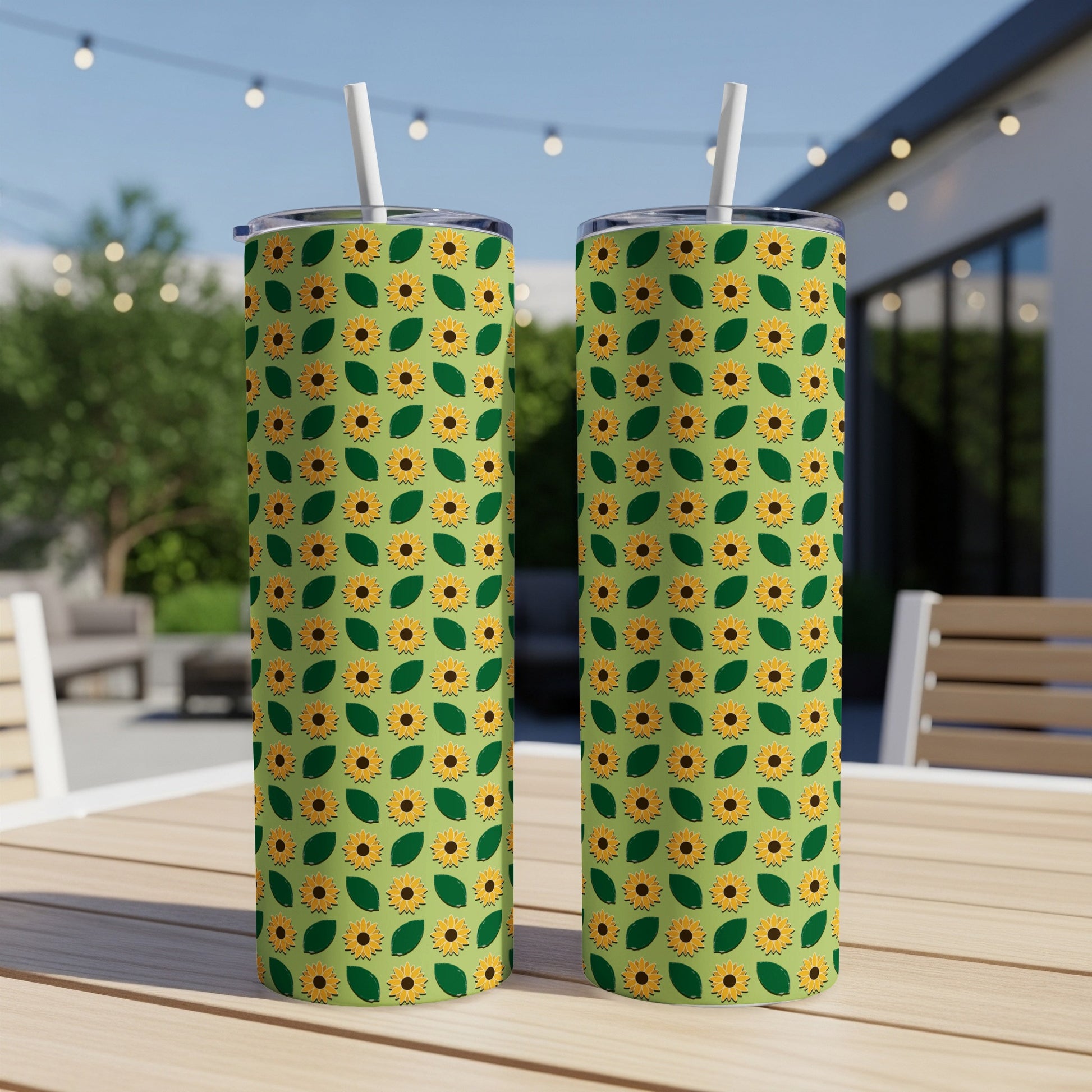 Two tall tumblers with a repeating sunflower and leaf pattern on a table.