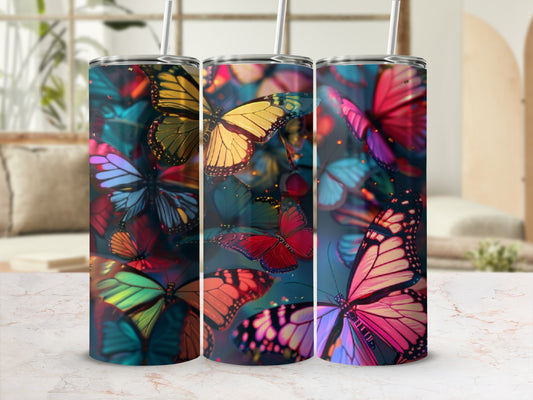 Colorful butterflies on a tumbler with straw against a blurred background.