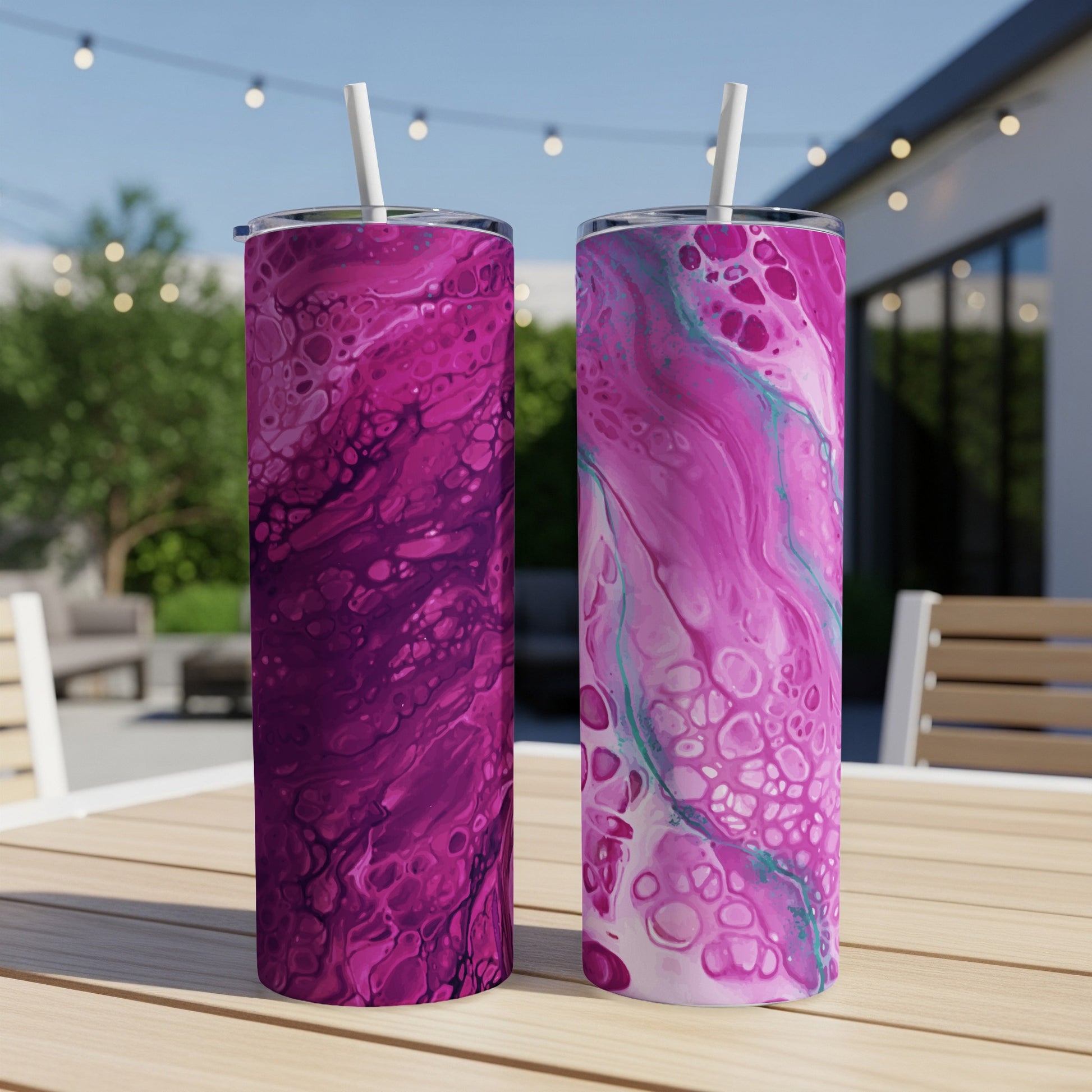 Two tumblers with abstract pink and purple fluid art designs sit on a table.