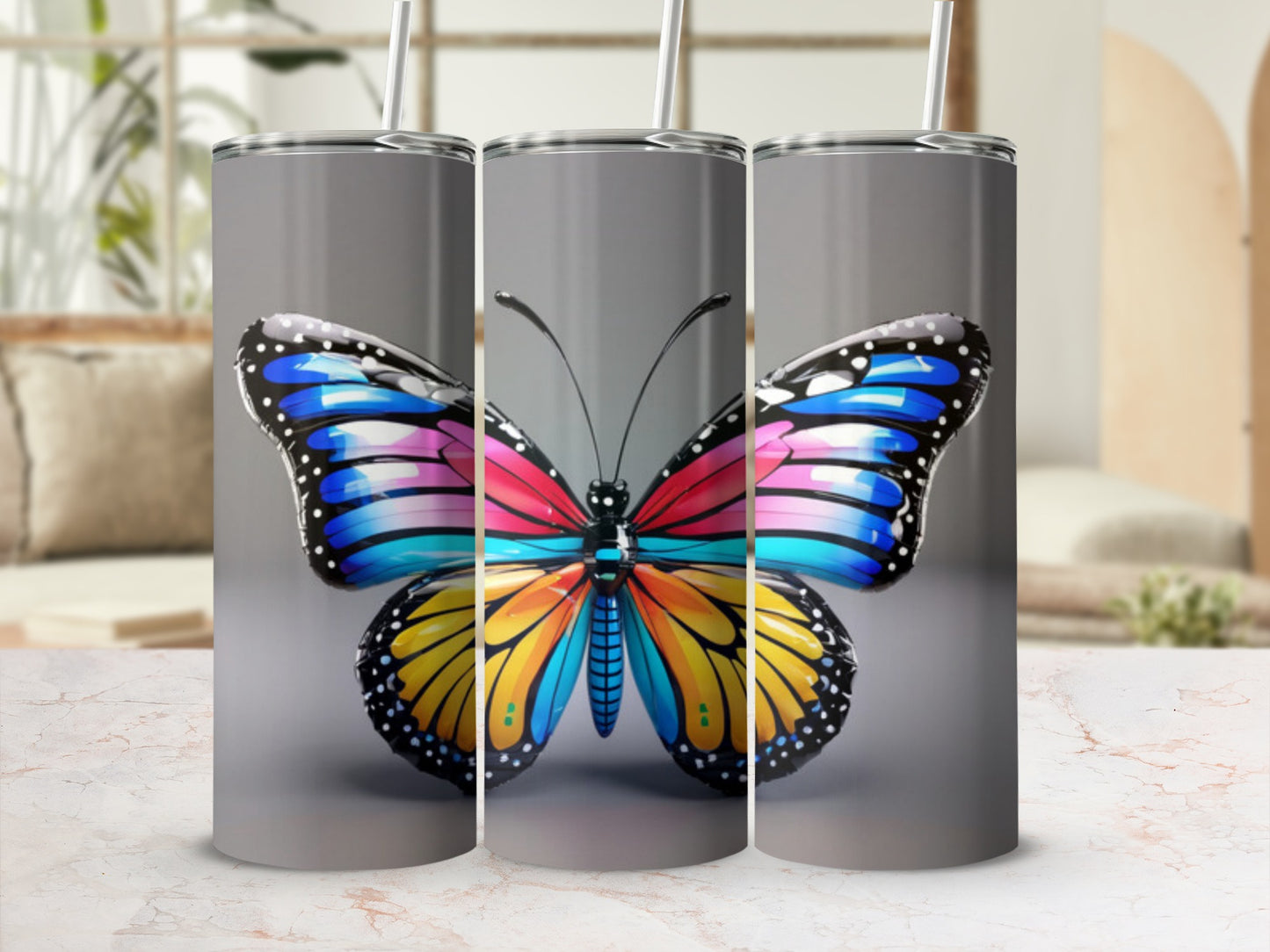 Butterfly graphic on a set of three silver tumblers with straws.