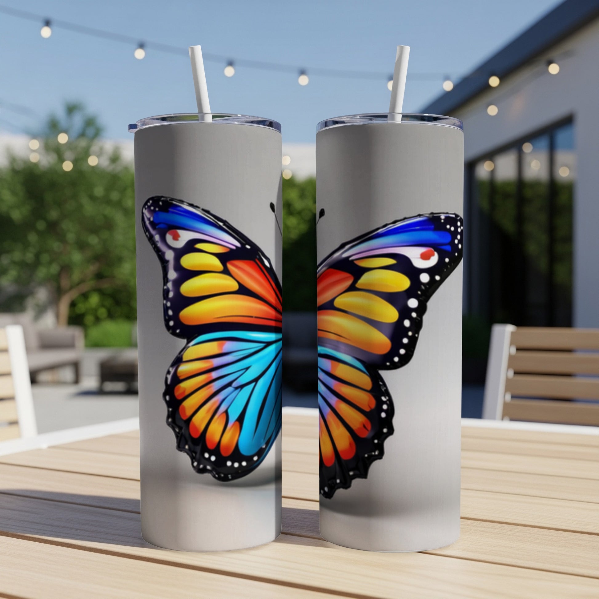 Two tumblers with a colorful butterfly design on a table.