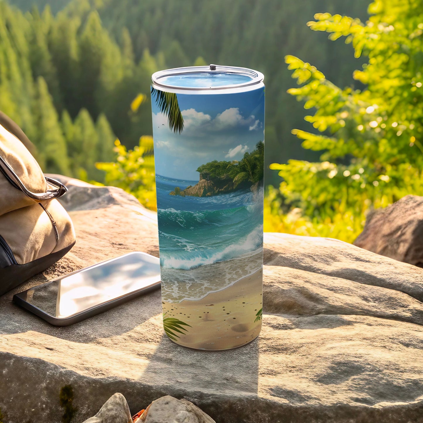 Tumbler with tropical beach scene on rock next to phone and bag.