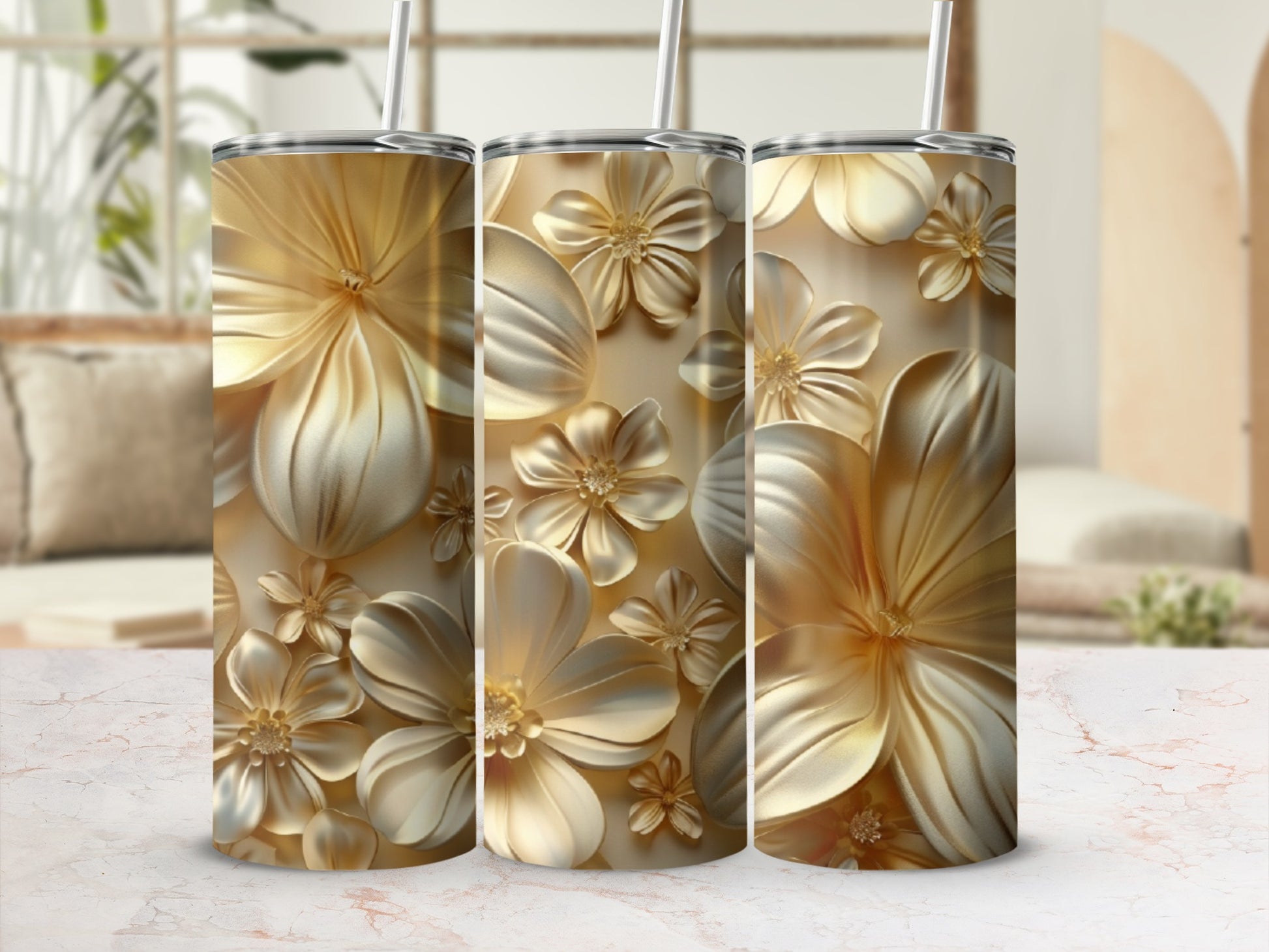 Three gold tumblers with raised floral patterns on a marble surface.