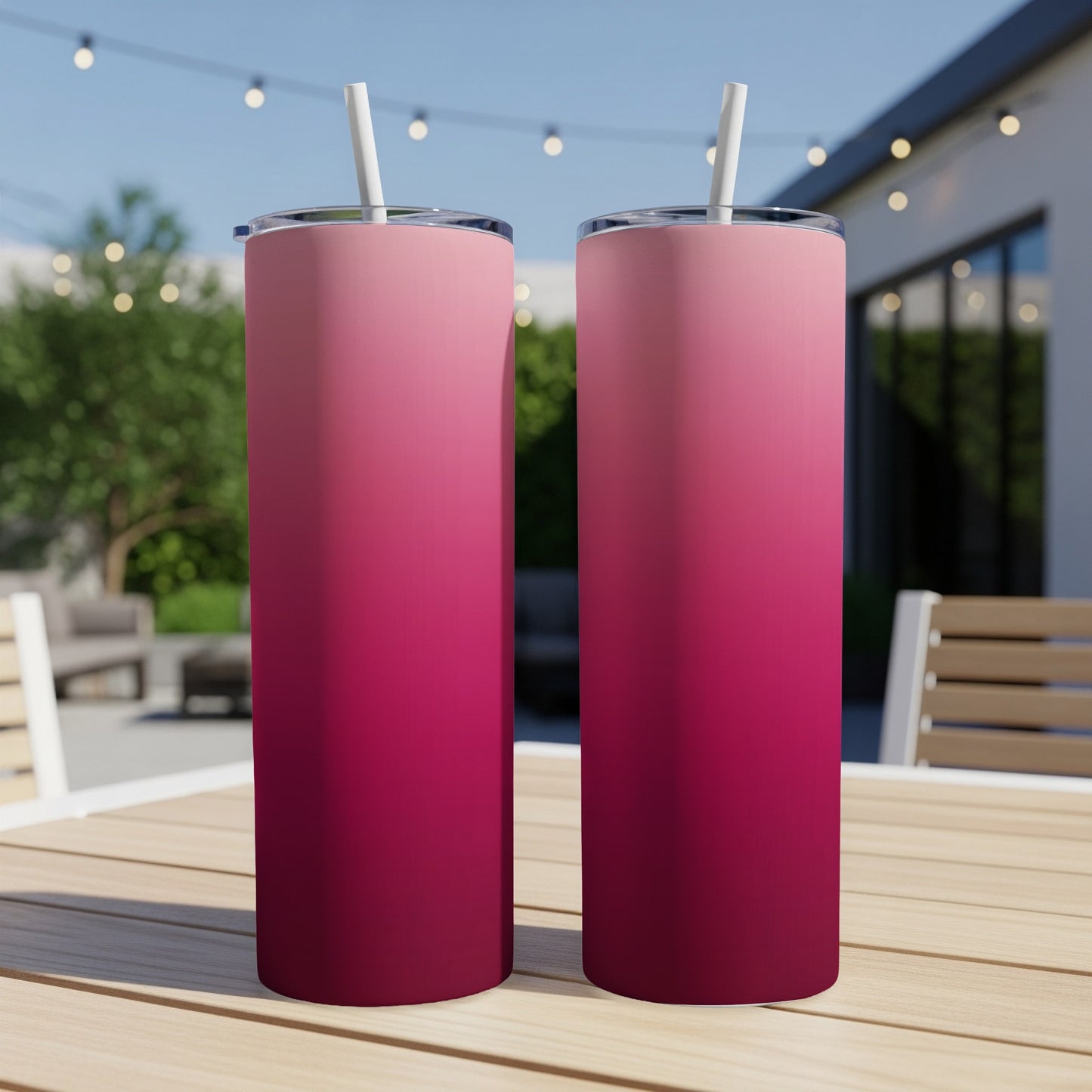 Two pink to dark red gradient tumblers with straws on a wooden table.