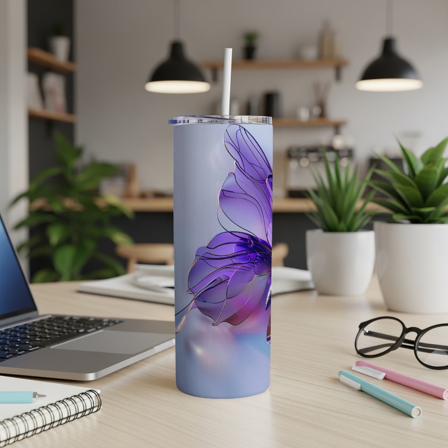 Tall tumbler with purple butterfly design and straw on desk.