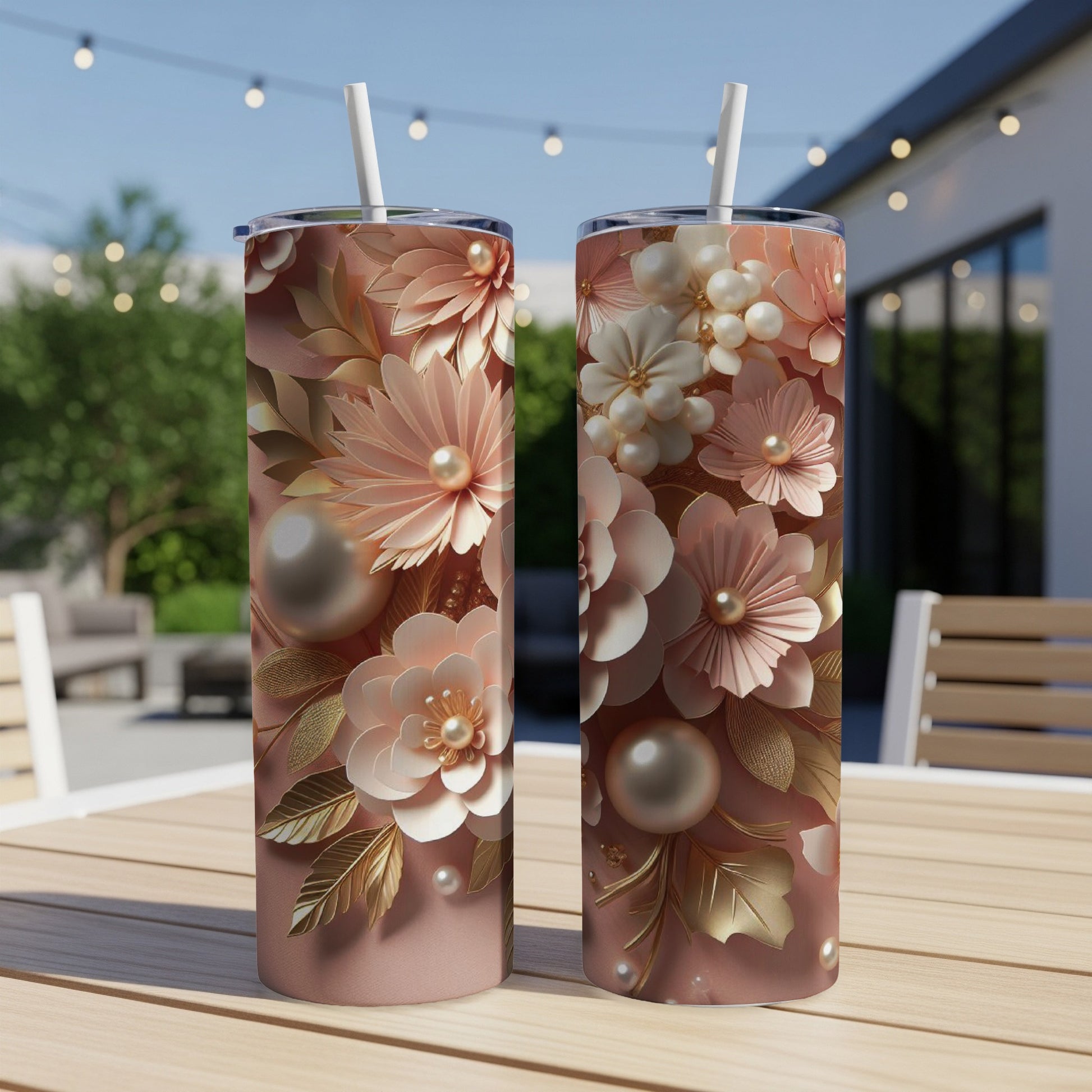 Two rose gold tumblers with floral and pearl embellishments sit on a table.