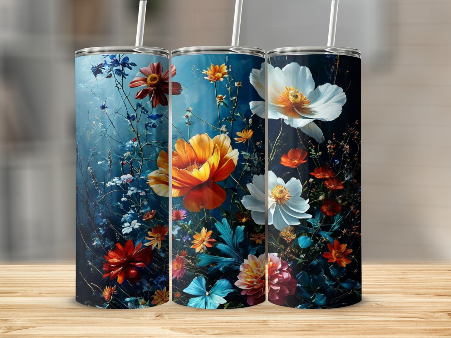 Three tumblers with vibrant floral designs on a wooden surface.