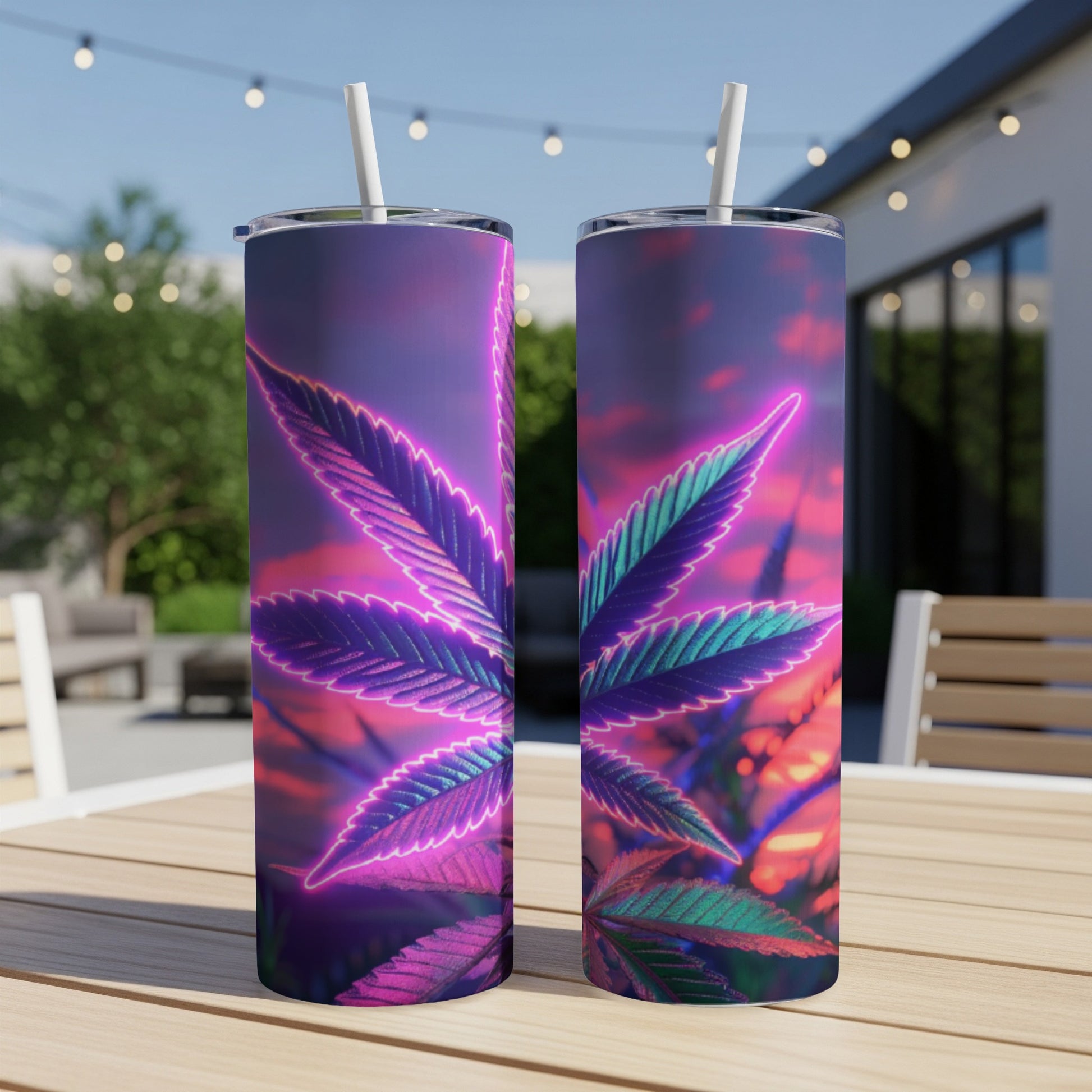 Two tumblers with neon cannabis leaf design on a patio table.