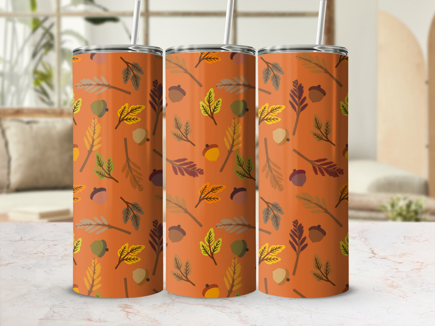 Three tumblers with autumn leaf and acorn pattern on orange background.