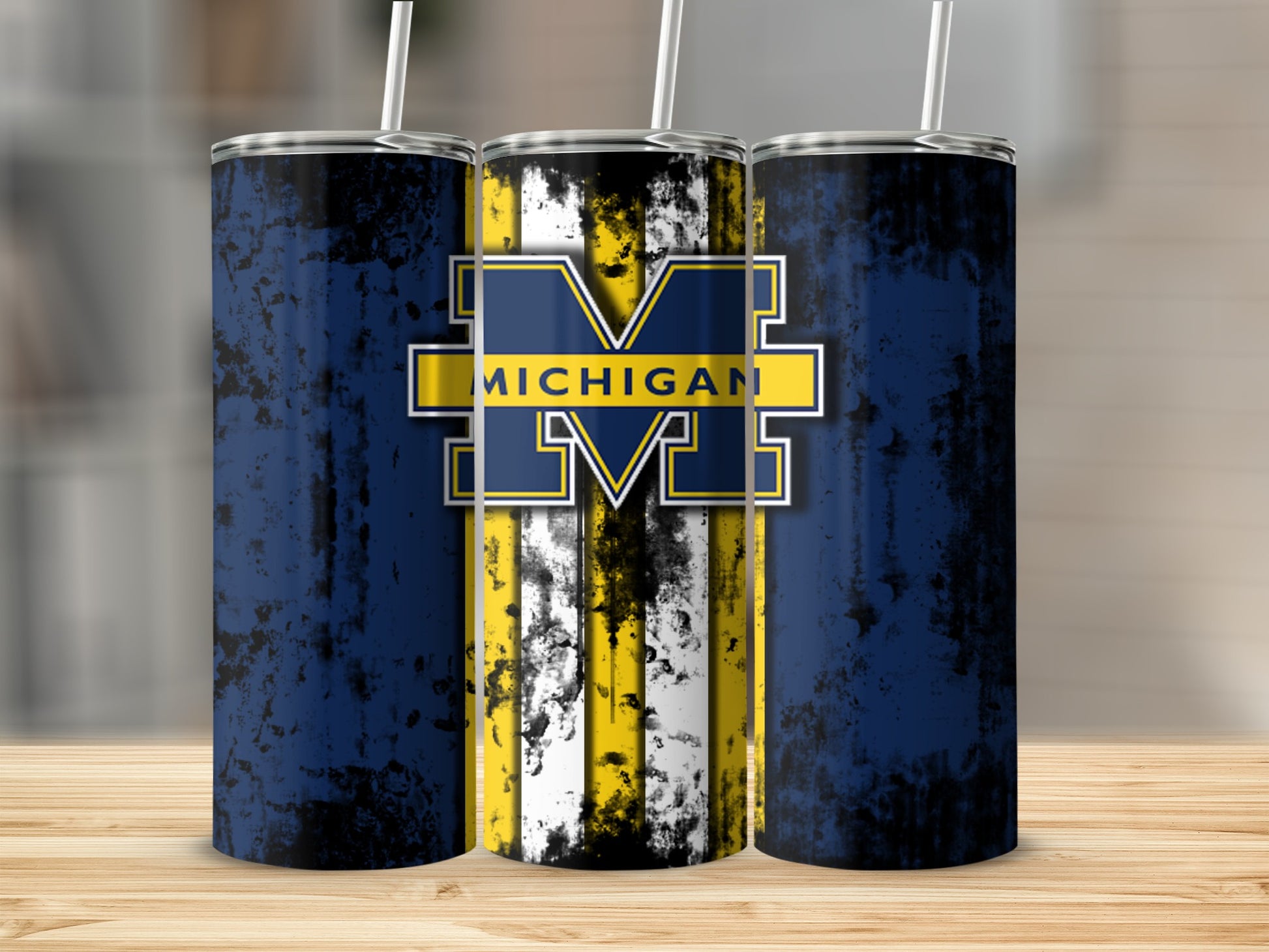 Michigan Wolverines logo and text on three distressed blue tumblers with straws