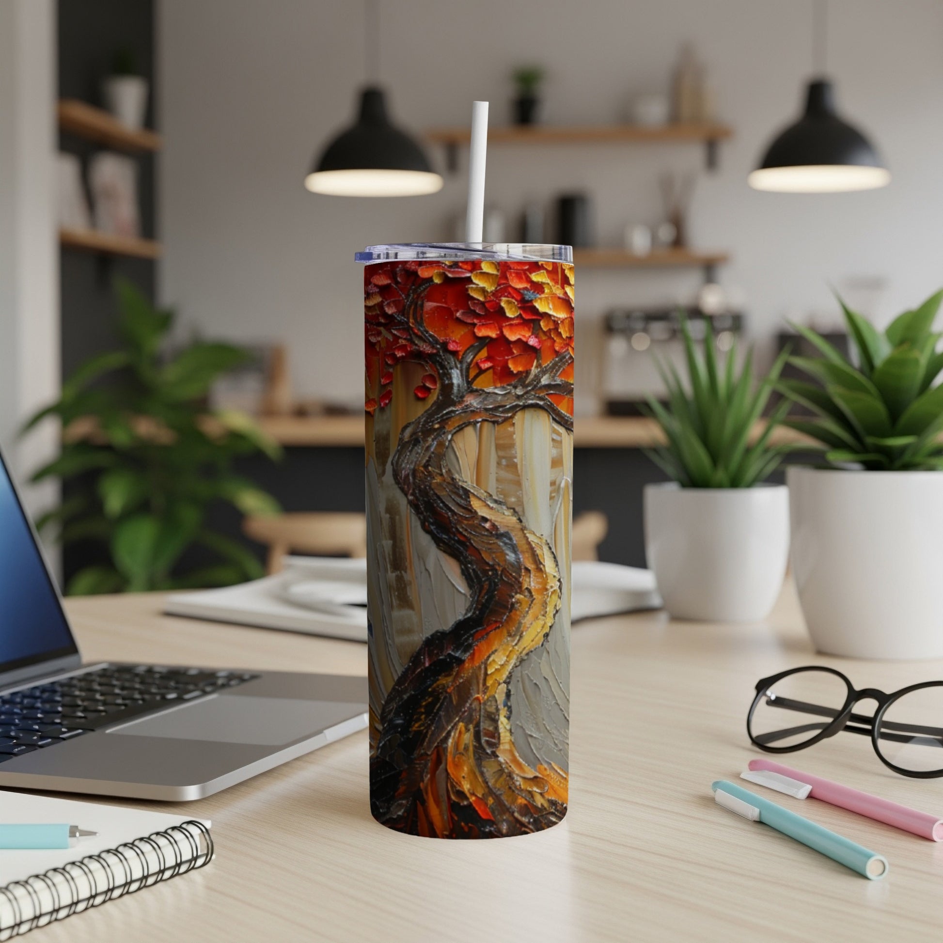 Textured tree artwork on a tumbler with a straw, on a desk.
