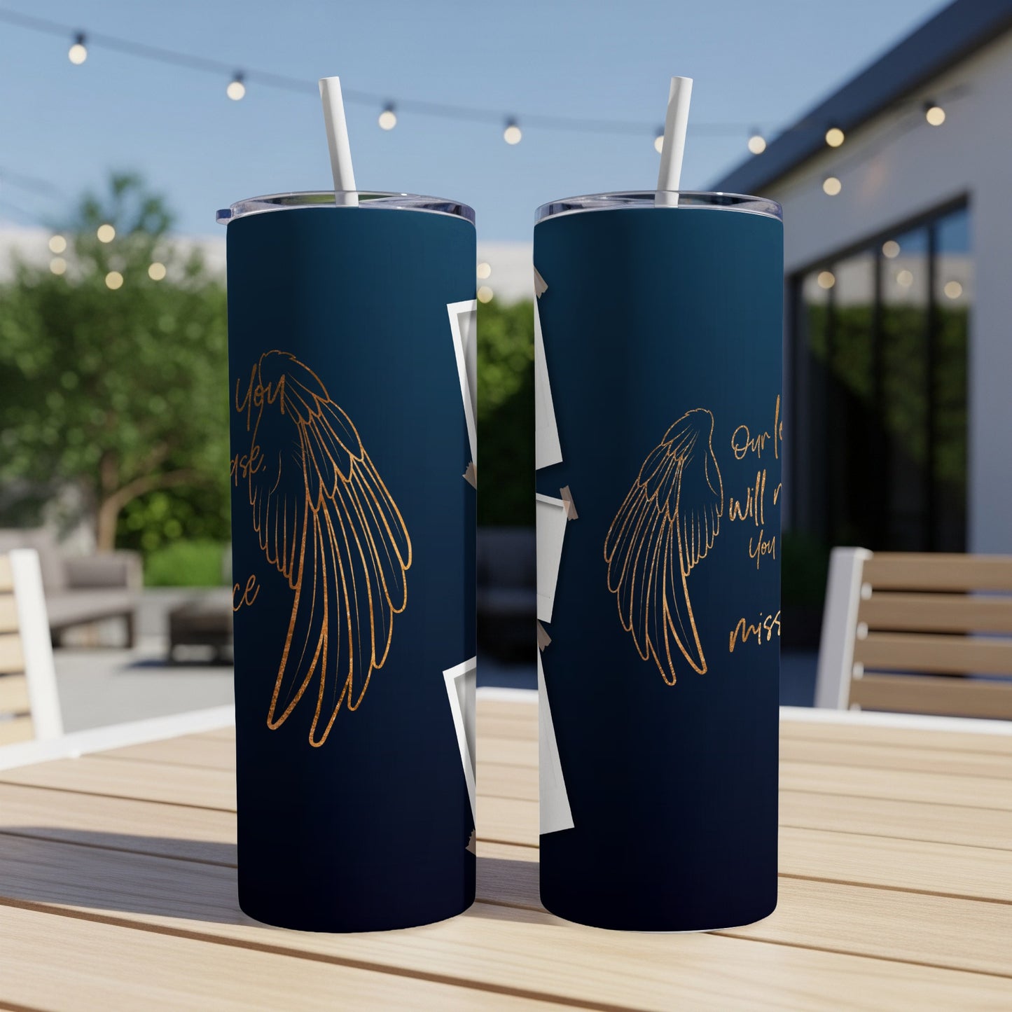 Two dark blue tumblers with gold wings and text on outdoor table.