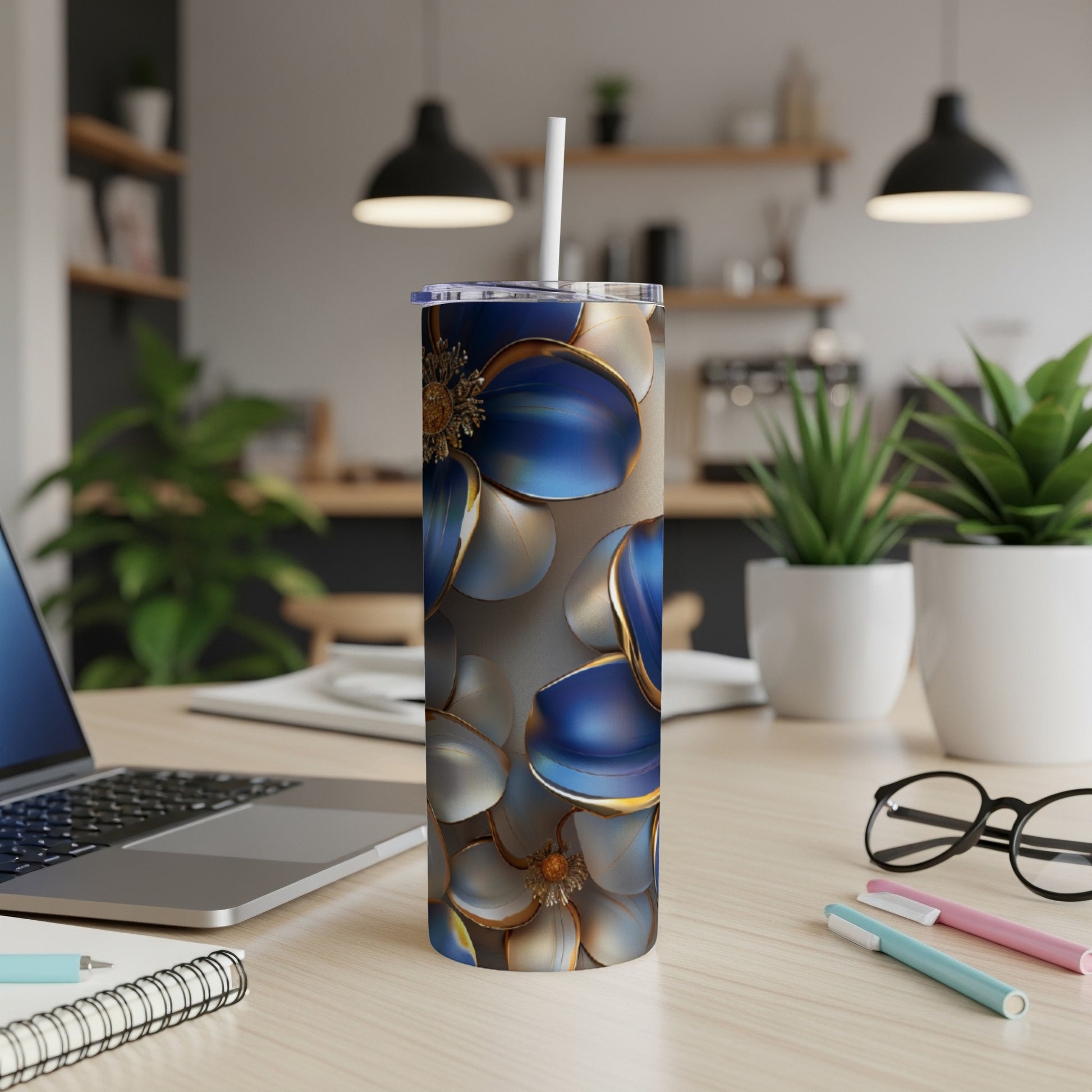 Blue and gold floral tumbler with straw on desk.