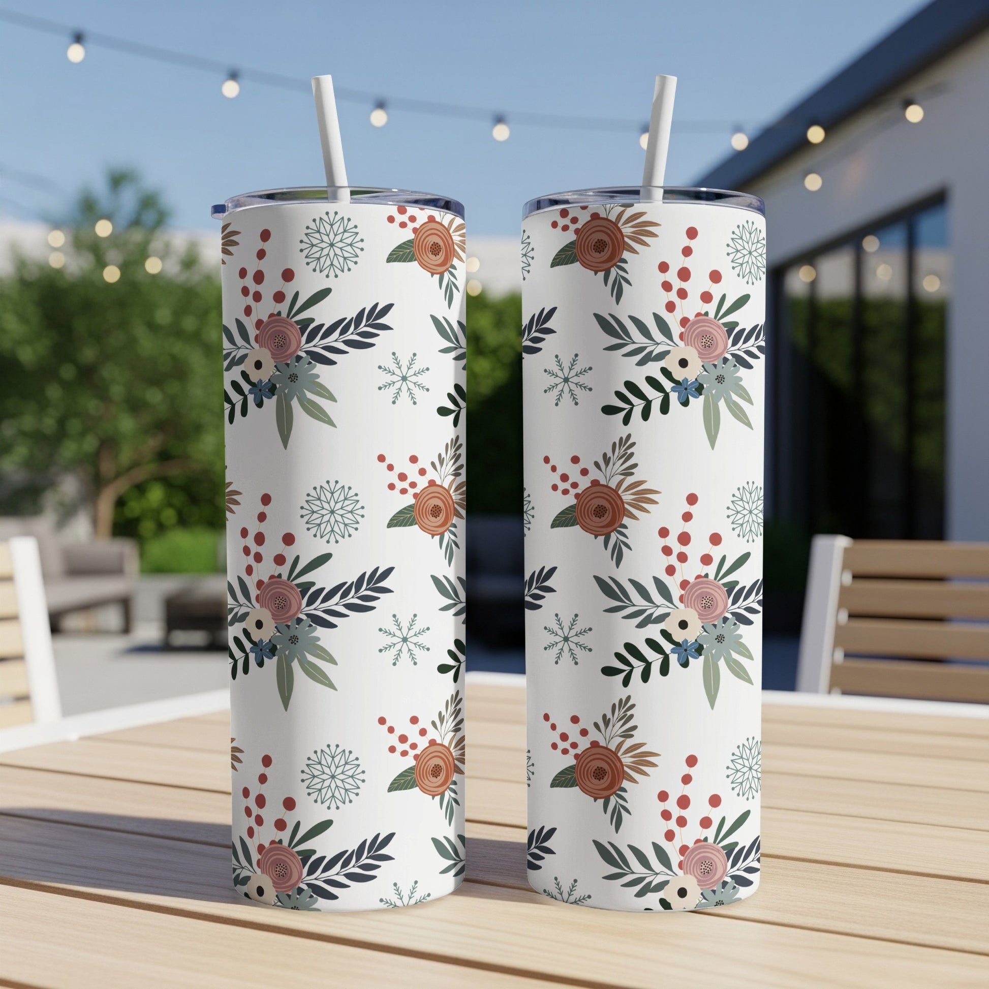 Two white tumblers with floral and snowflake pattern on a table.